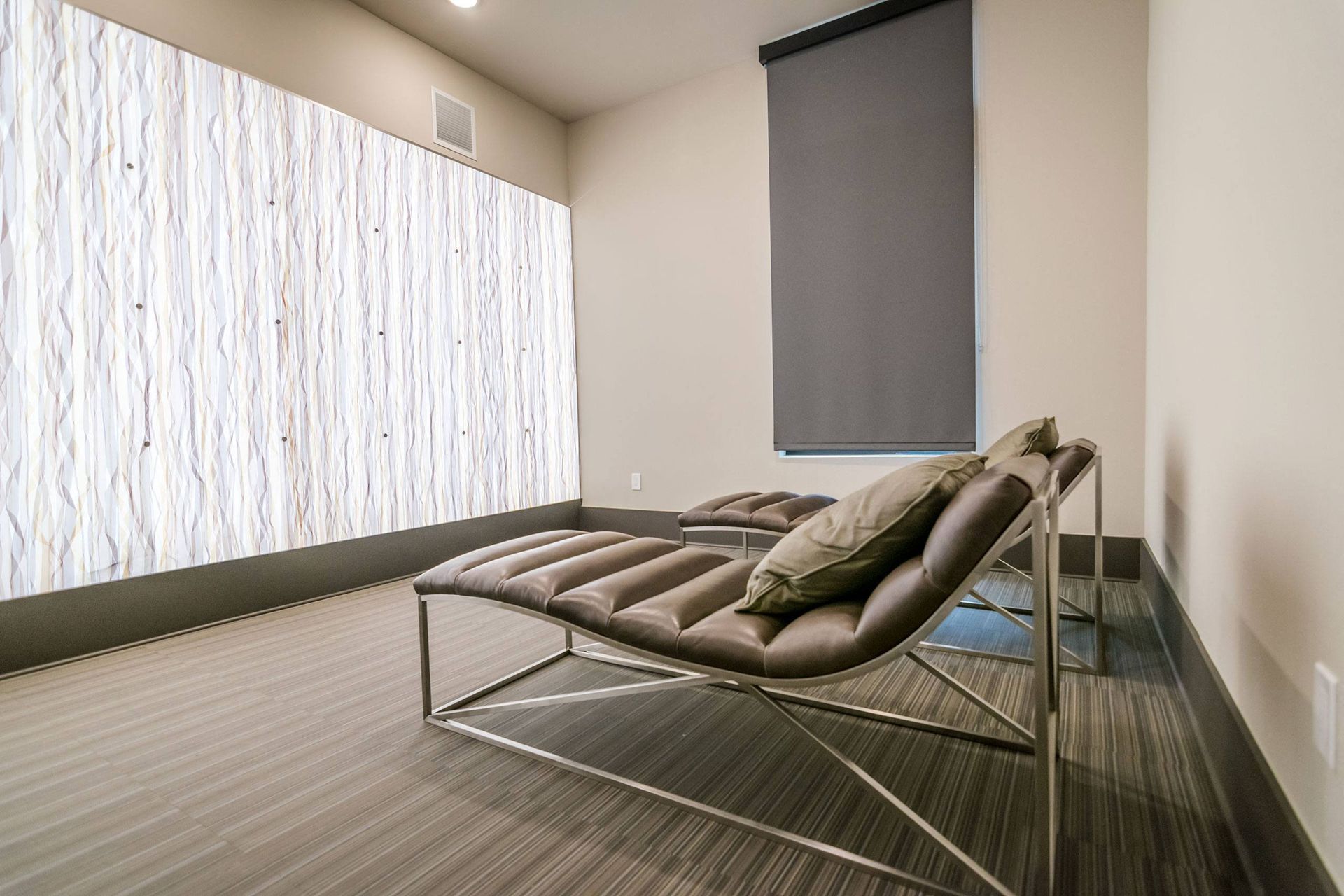 A lounge chair is sitting in a room next to a window.