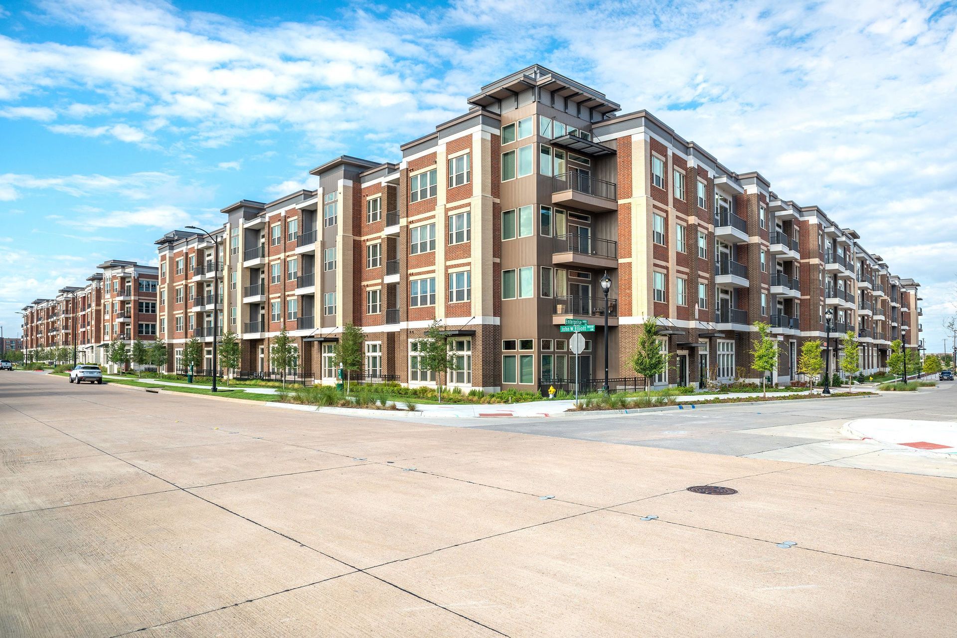 A large apartment building is sitting on the corner of a street.