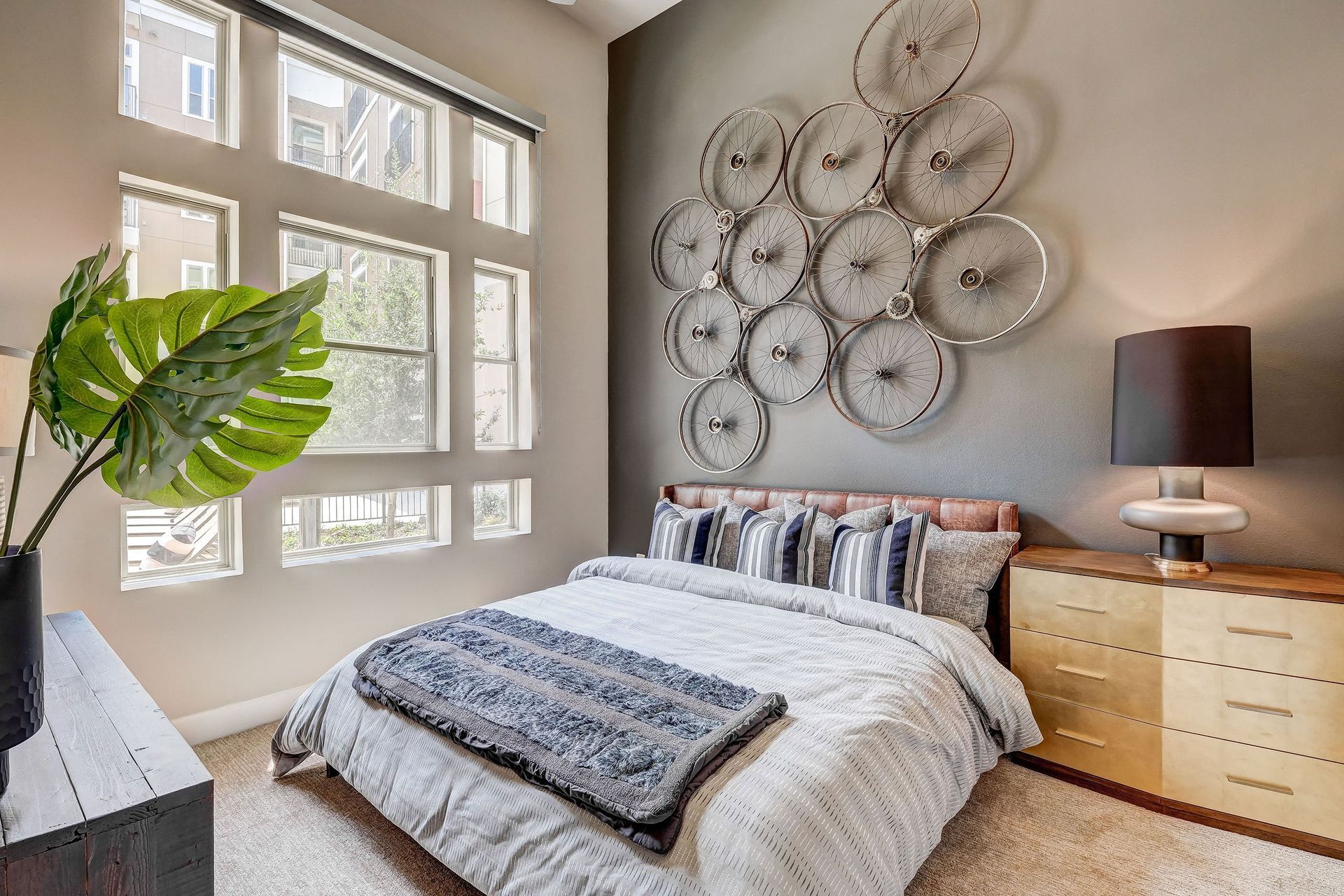 A bedroom with a bed, dresser, lamp, and clocks on the wall.