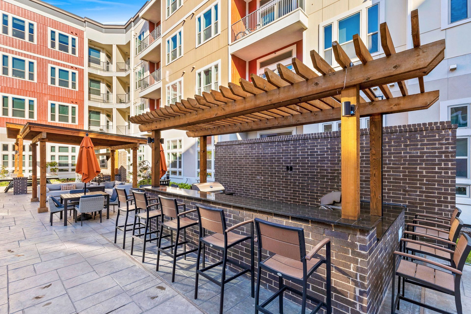 A patio area with a bar and chairs in front of a building.