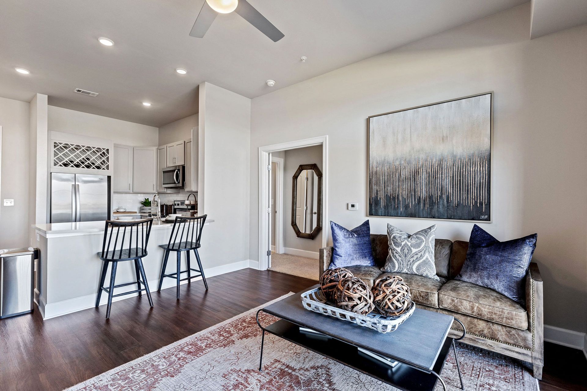 A living room with a couch , coffee table , stools and a ceiling fan.