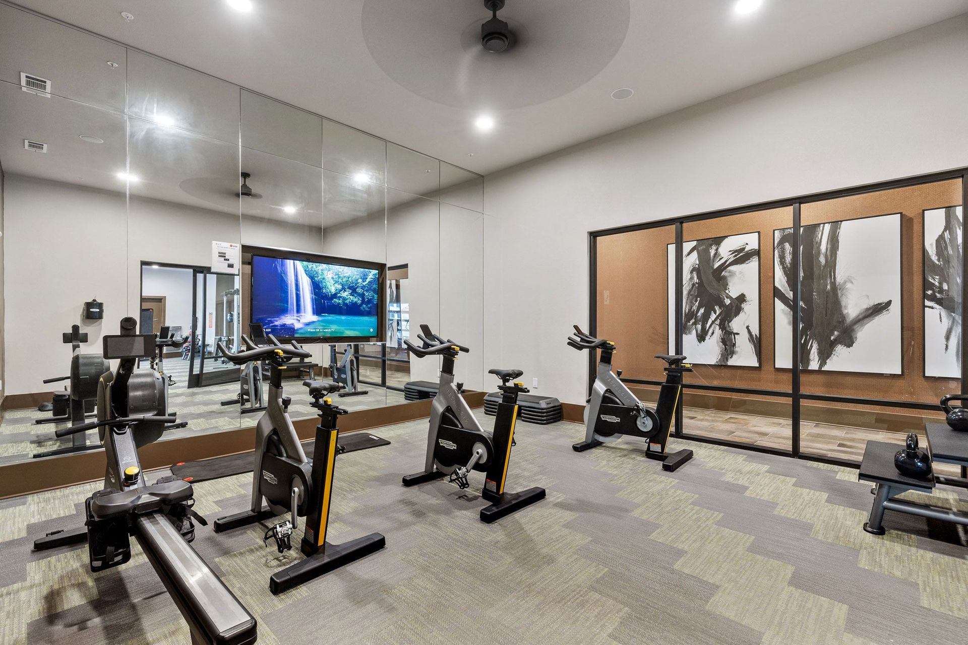 A gym with a lot of exercise bikes and a large mirror.