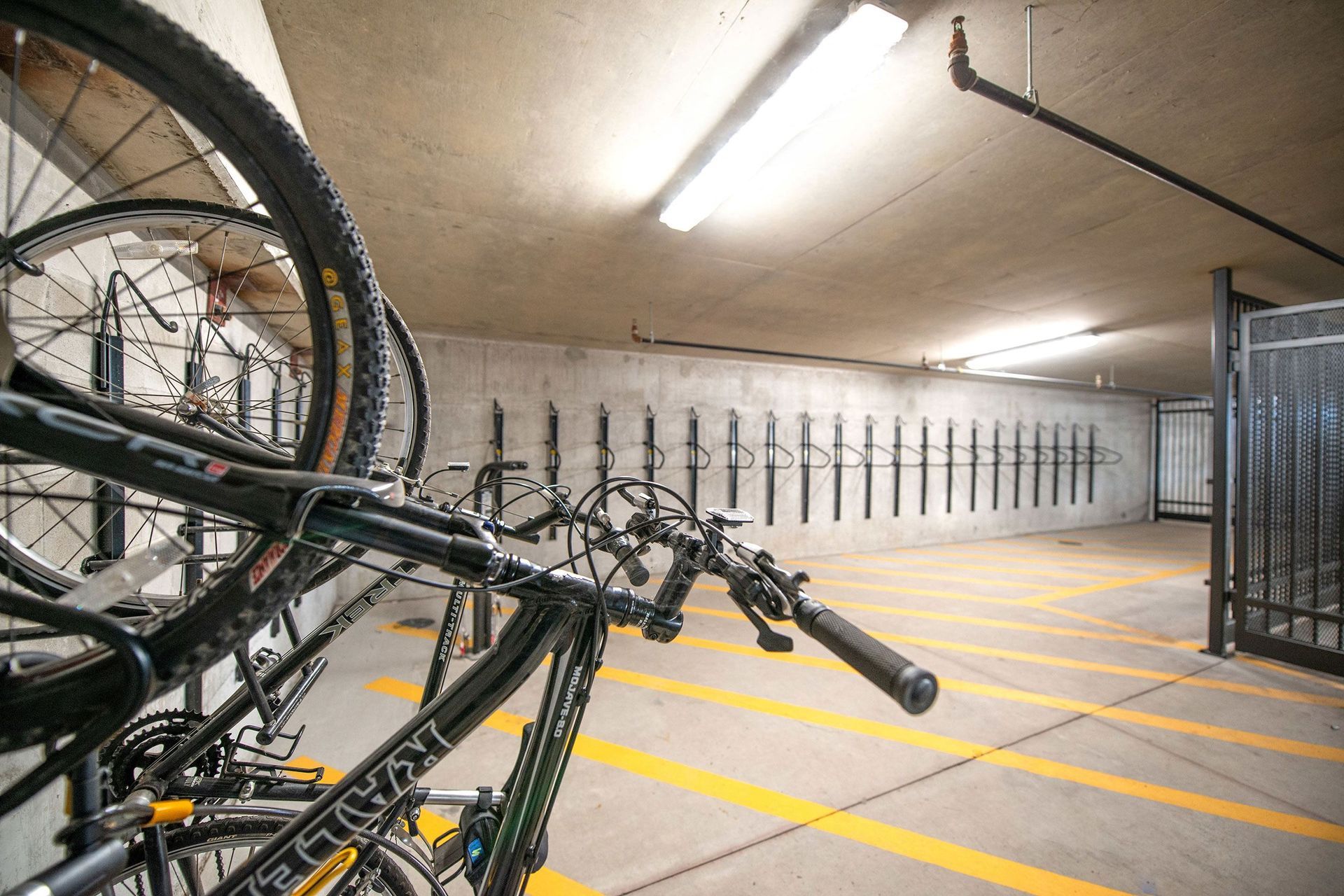 A row of bicycles are parked in a parking garage.