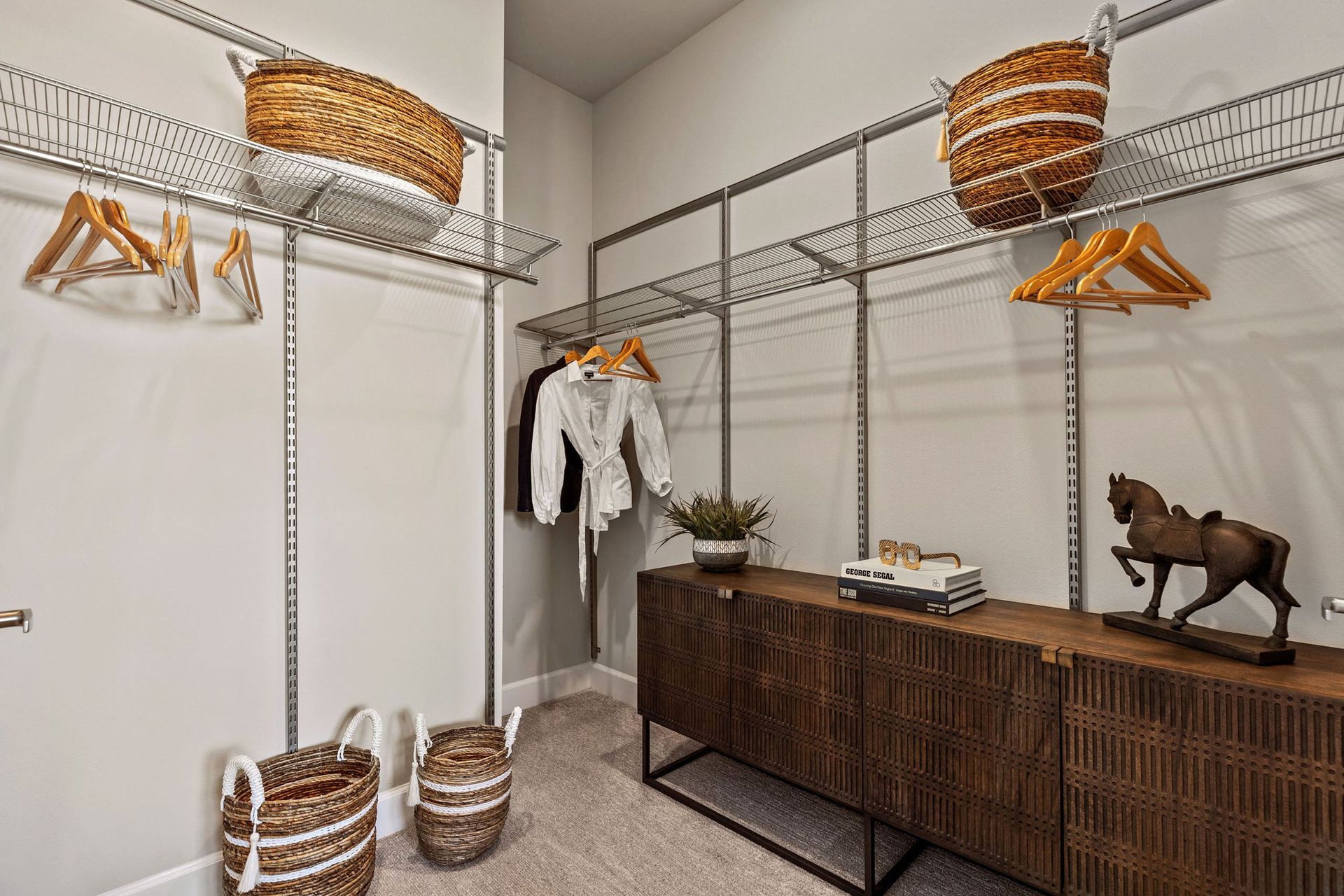 A walk in closet with clothes hanging on racks and baskets.
