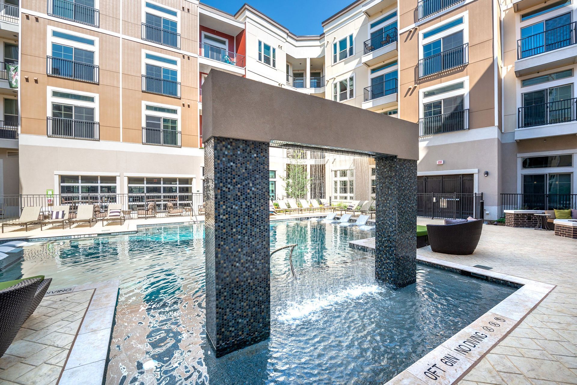 A large swimming pool with a waterfall in the middle of it in front of a building.