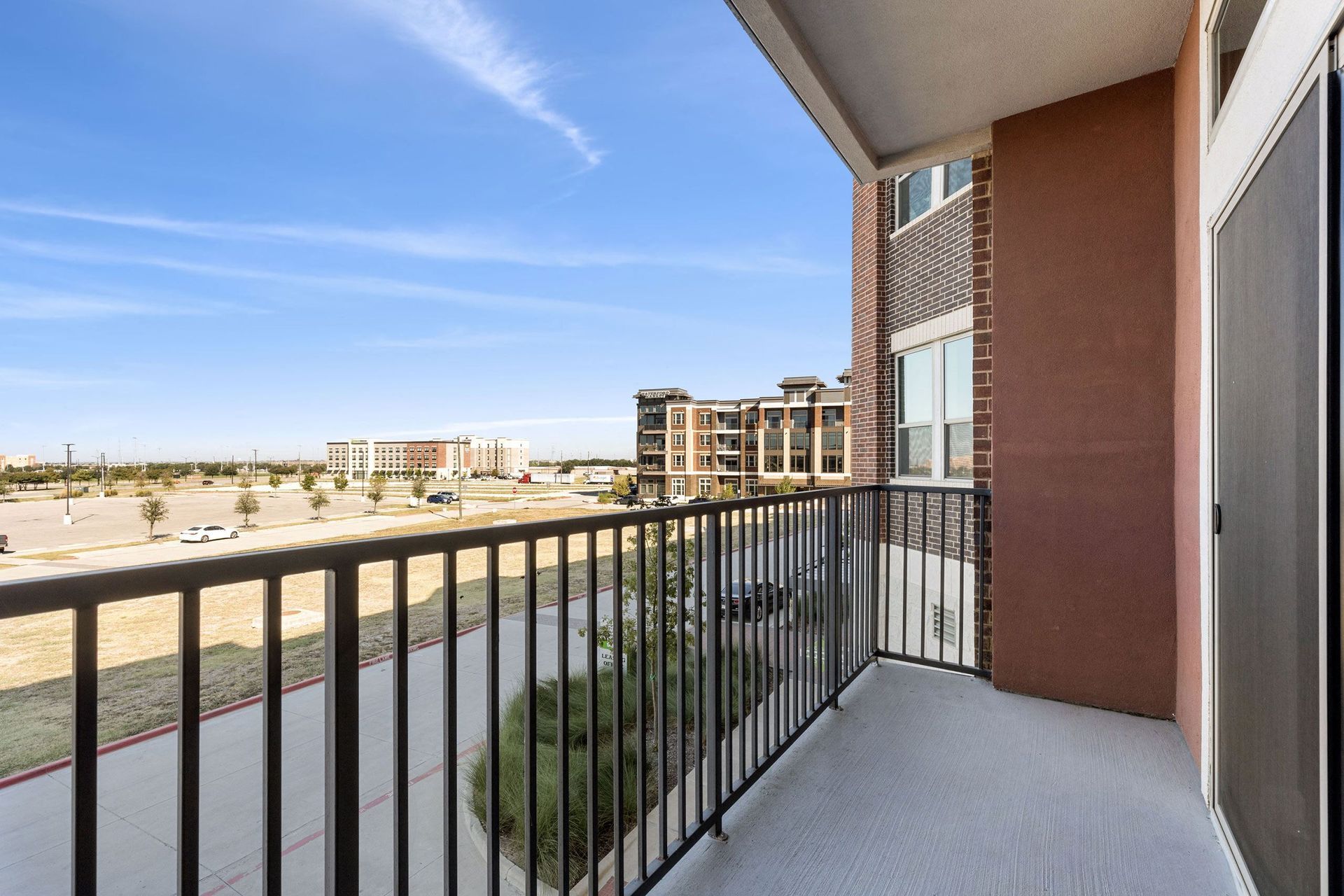 A balcony with a metal railing and a view of a city.