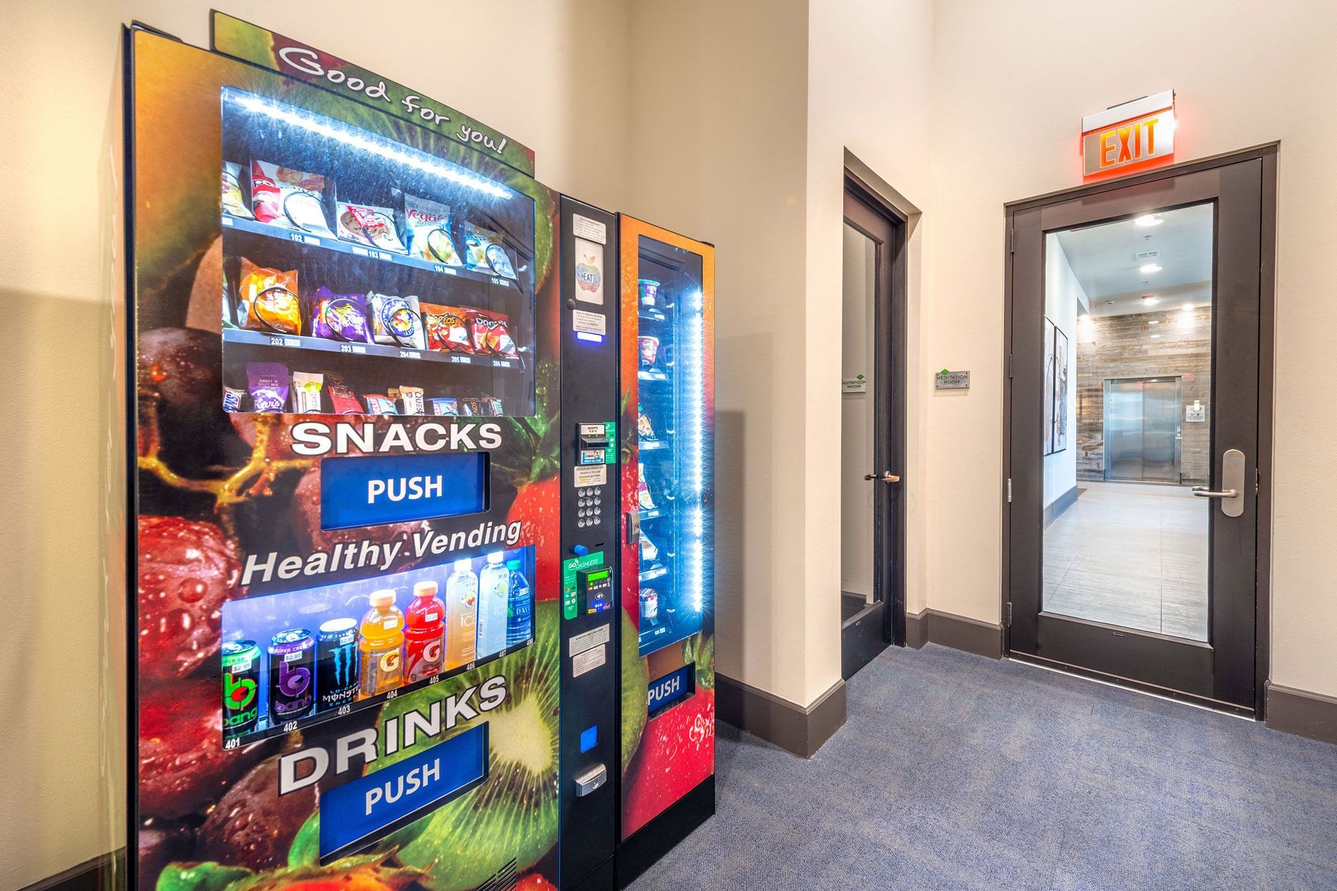 A vending machine selling snacks and drinks in a hallway.
