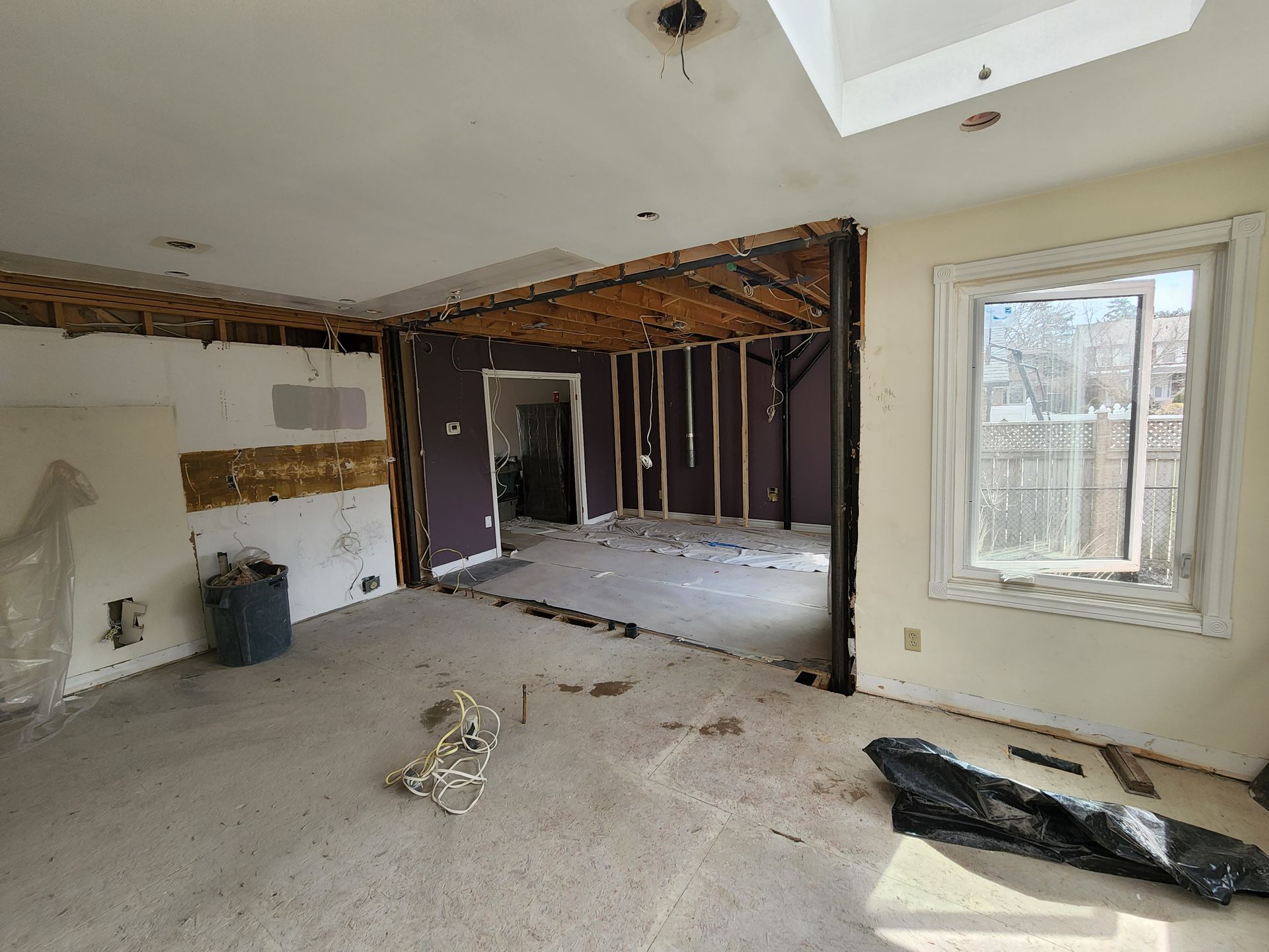 An empty living room with a purple wall and a window.