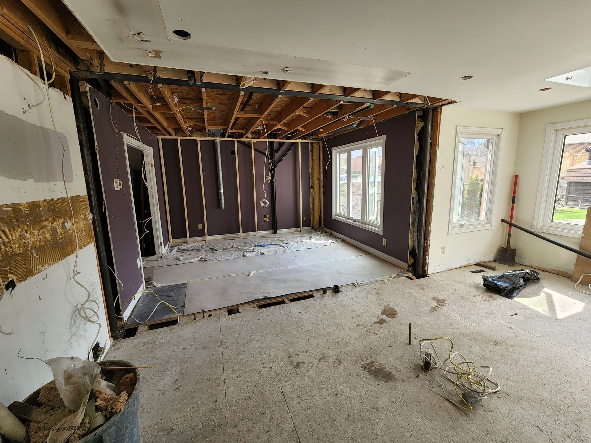 A living room with purple walls and white carpet is being remodeled.