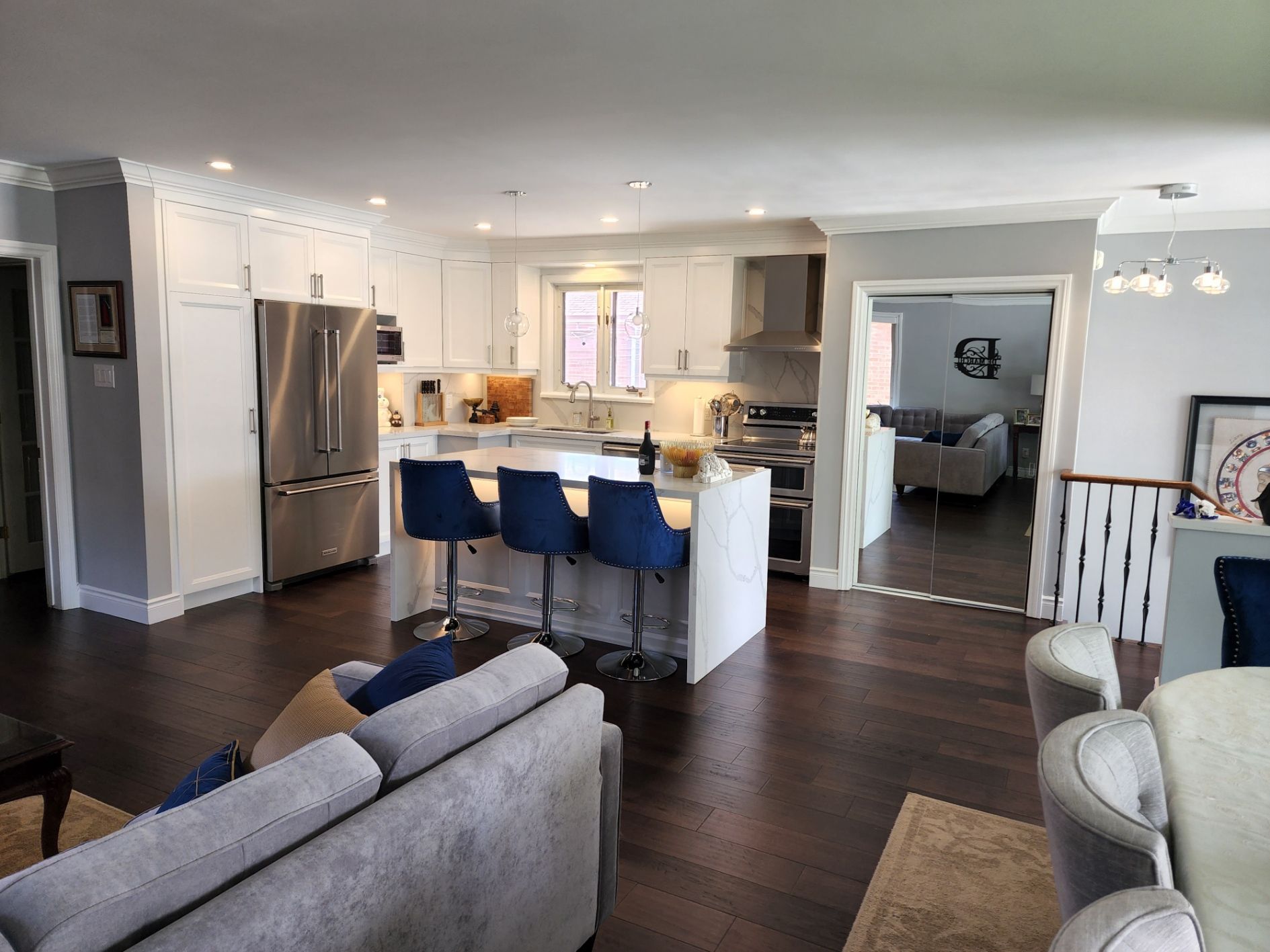 A living room with a couch , chairs , and a kitchen.