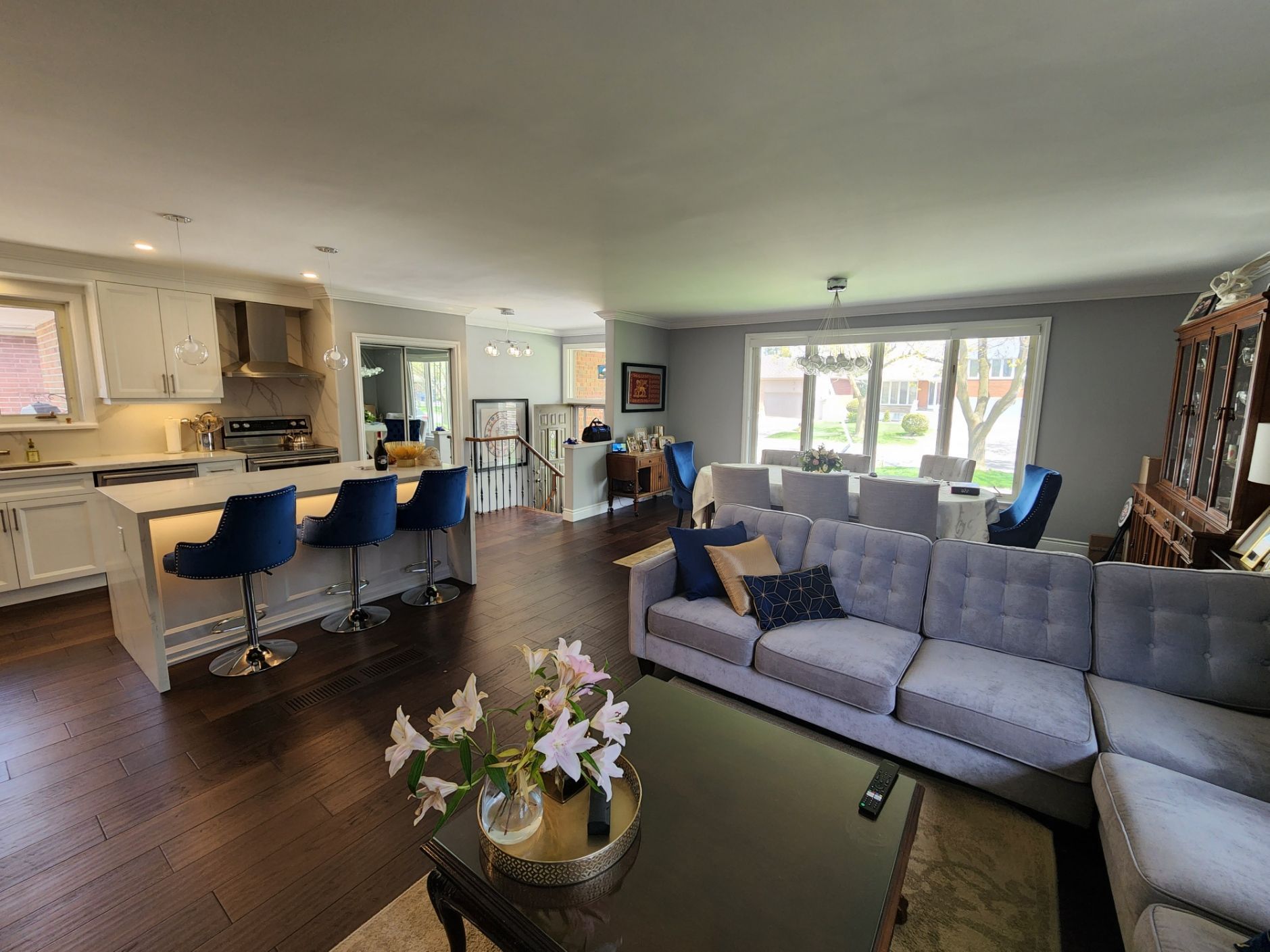 A living room with a couch , table , chairs and a kitchen.