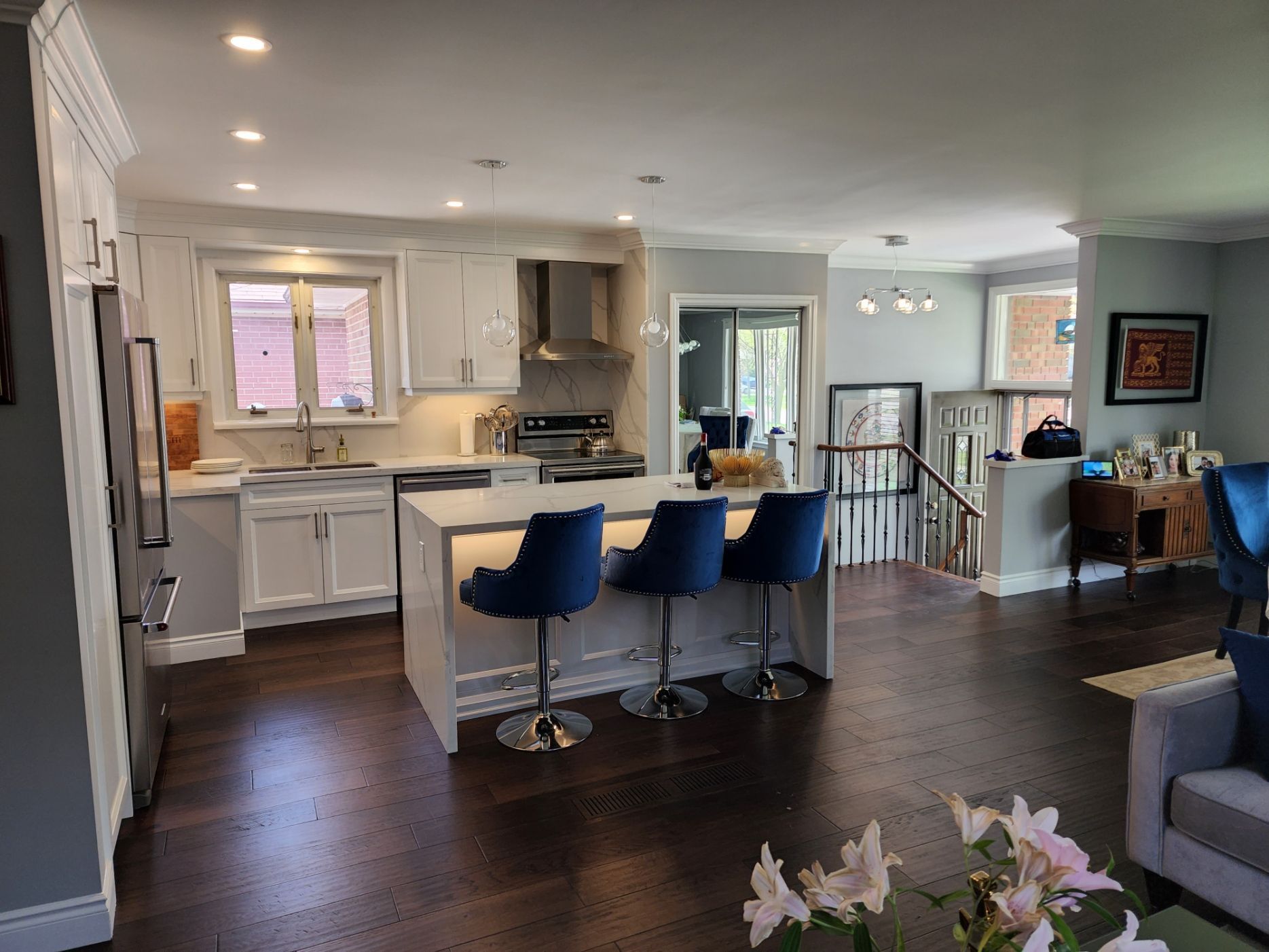 A kitchen with a large island and blue chairs in a living room.