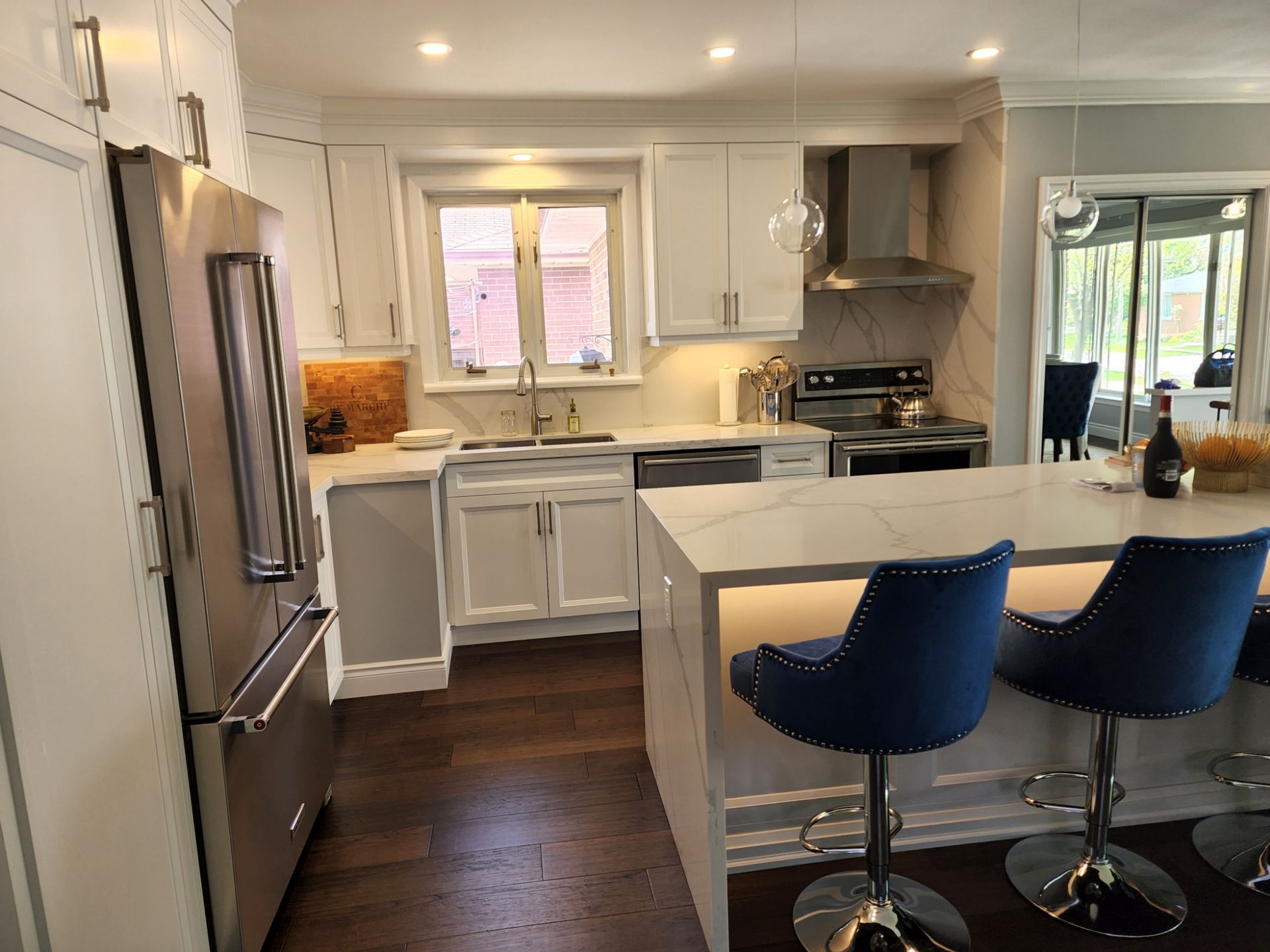A kitchen with white cabinets , stainless steel appliances , and a large island.
