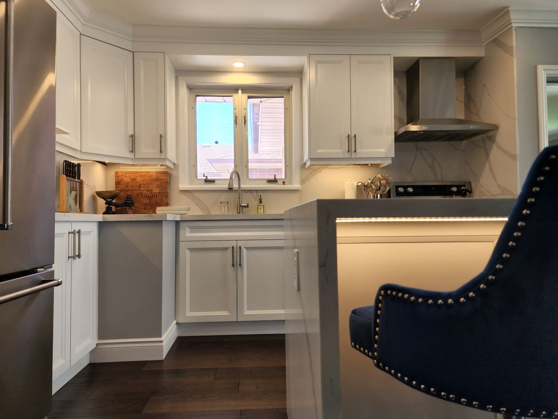 A kitchen with white cabinets and a blue chair