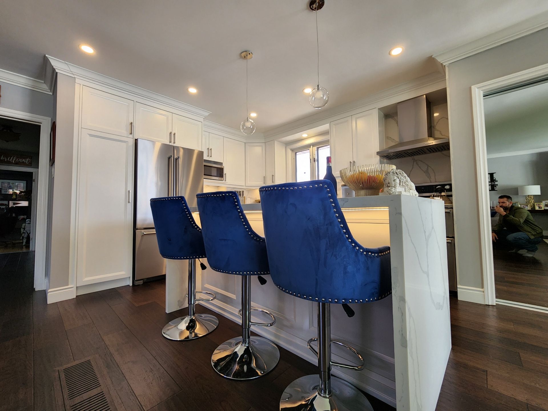 A kitchen with a large island and blue bar stools.