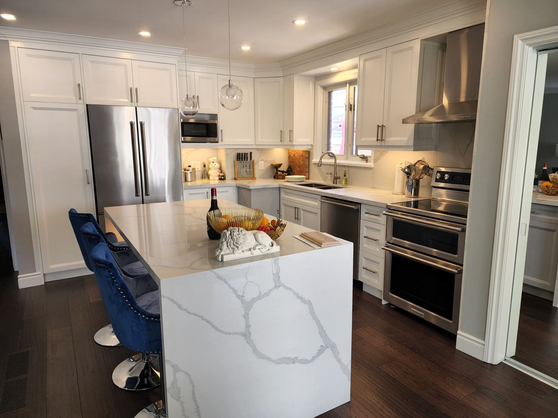A kitchen with white cabinets , stainless steel appliances and a large island.