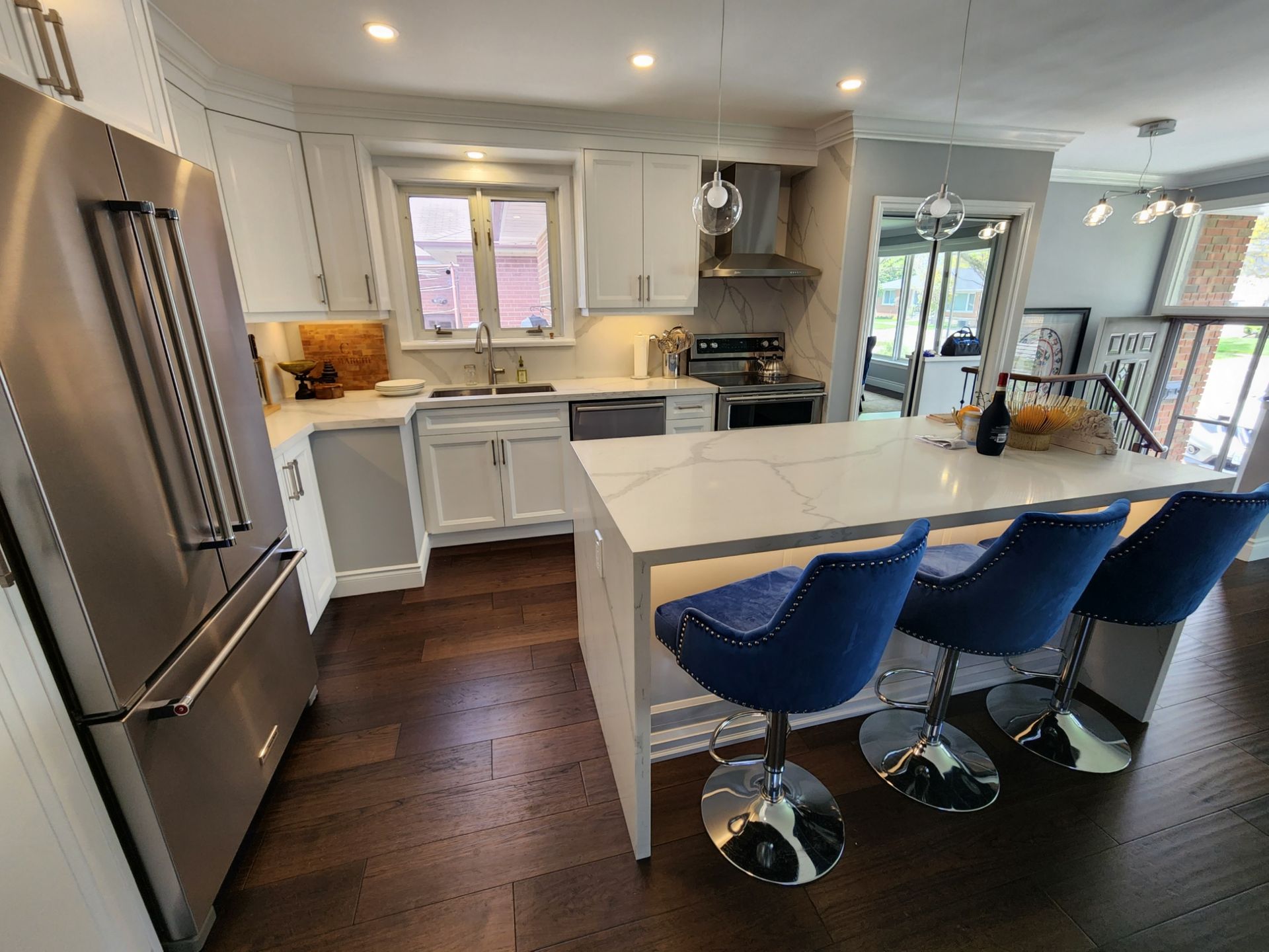 A kitchen with stainless steel appliances , white cabinets , and blue chairs.