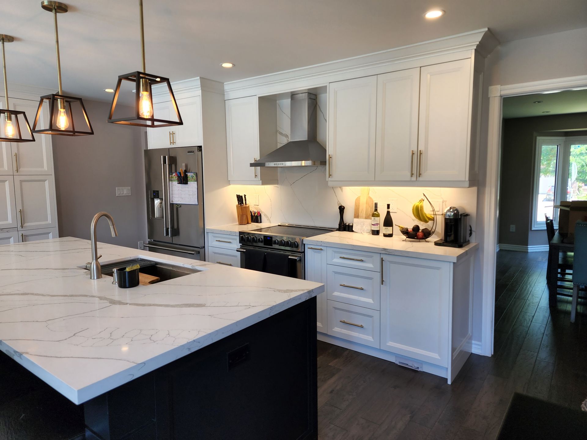 A kitchen with white cabinets , stainless steel appliances , and a large island.