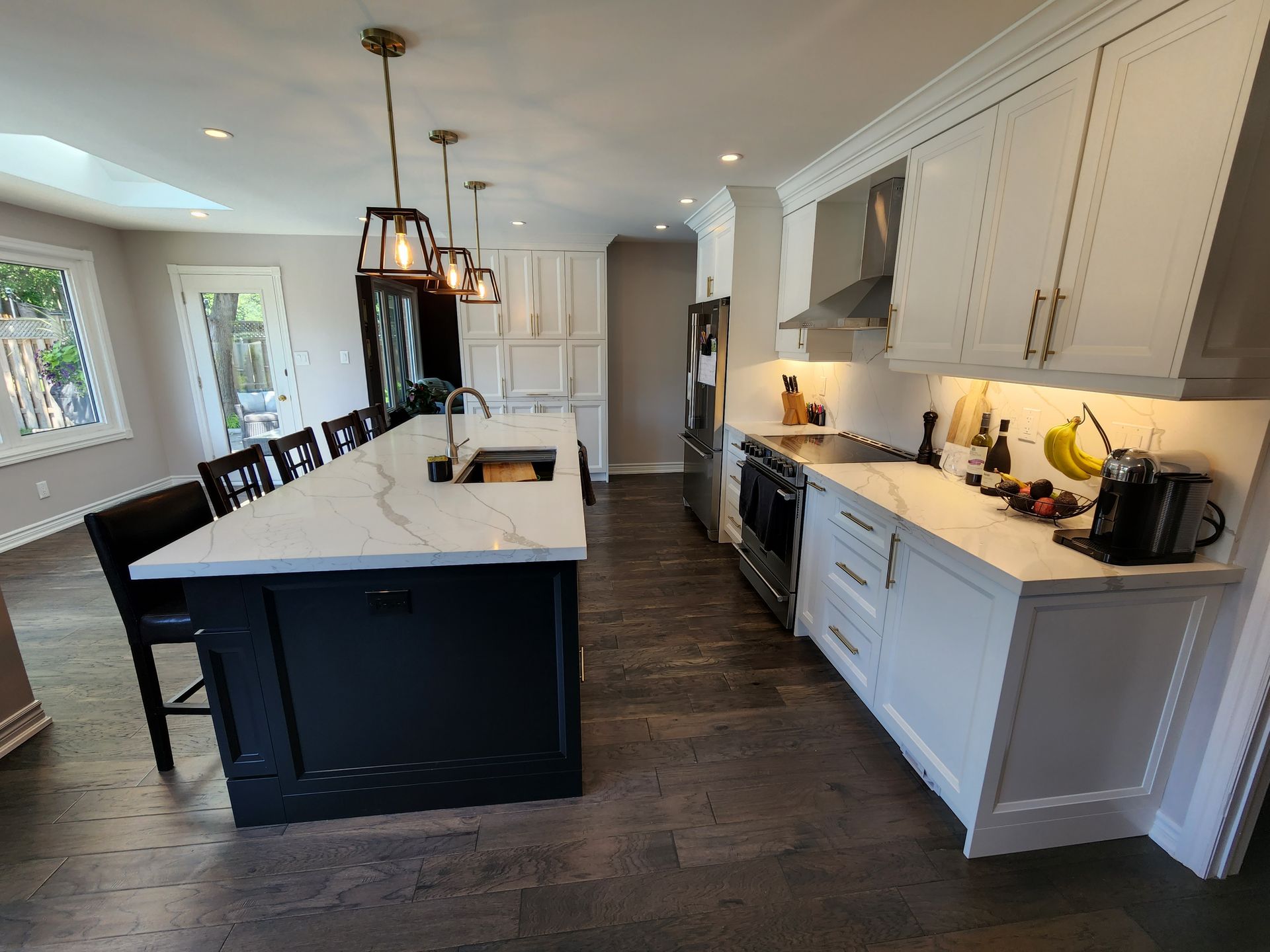 A kitchen with white cabinets and stainless steel appliances and a large island.