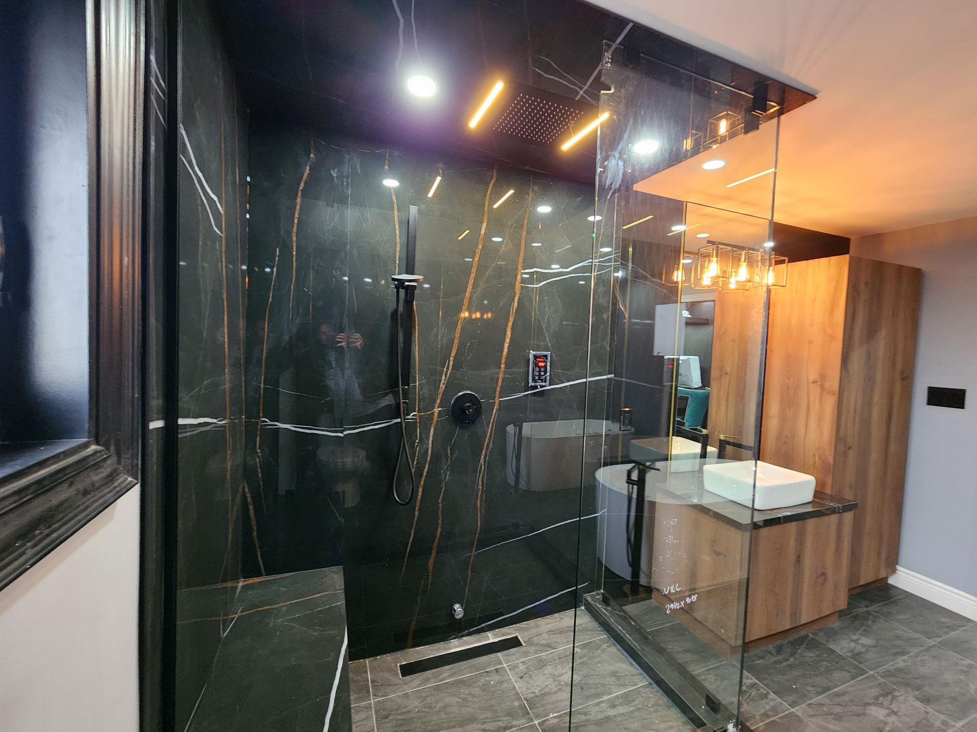 A bathroom with a walk in shower , sink and mirror.