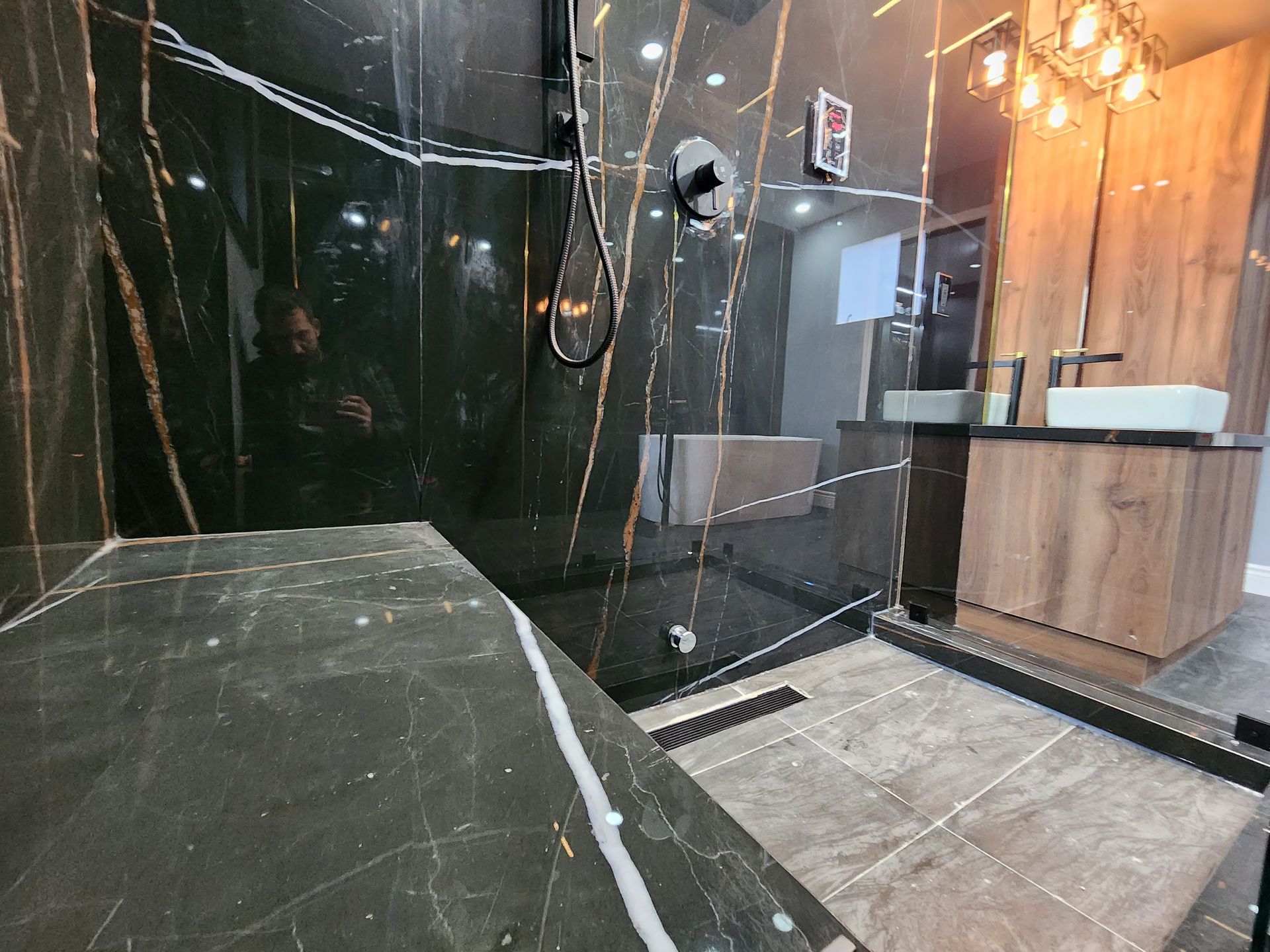 A bathroom with a walk in shower , sink and mirror.