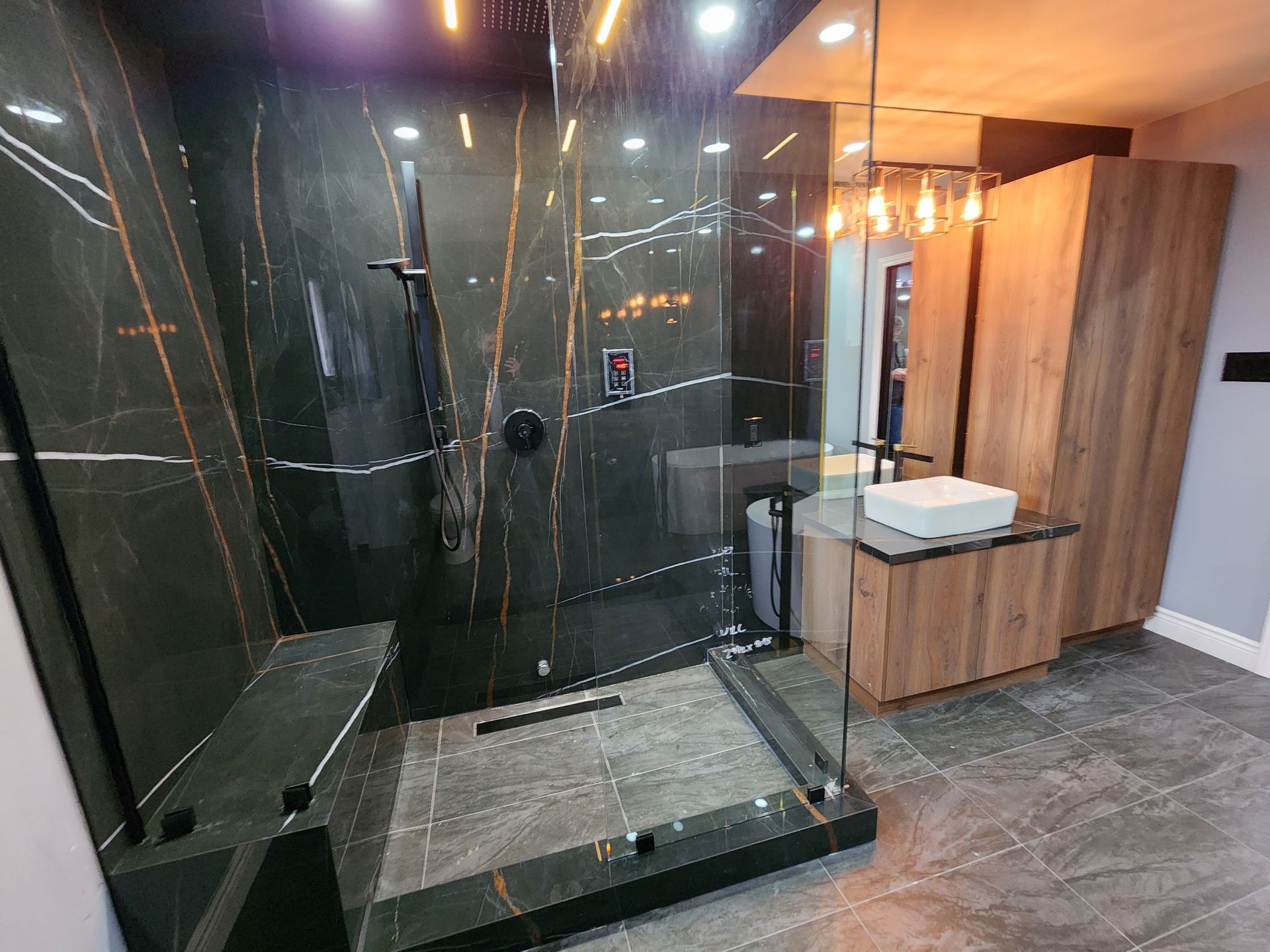 A bathroom with a walk in shower , sink and mirror.