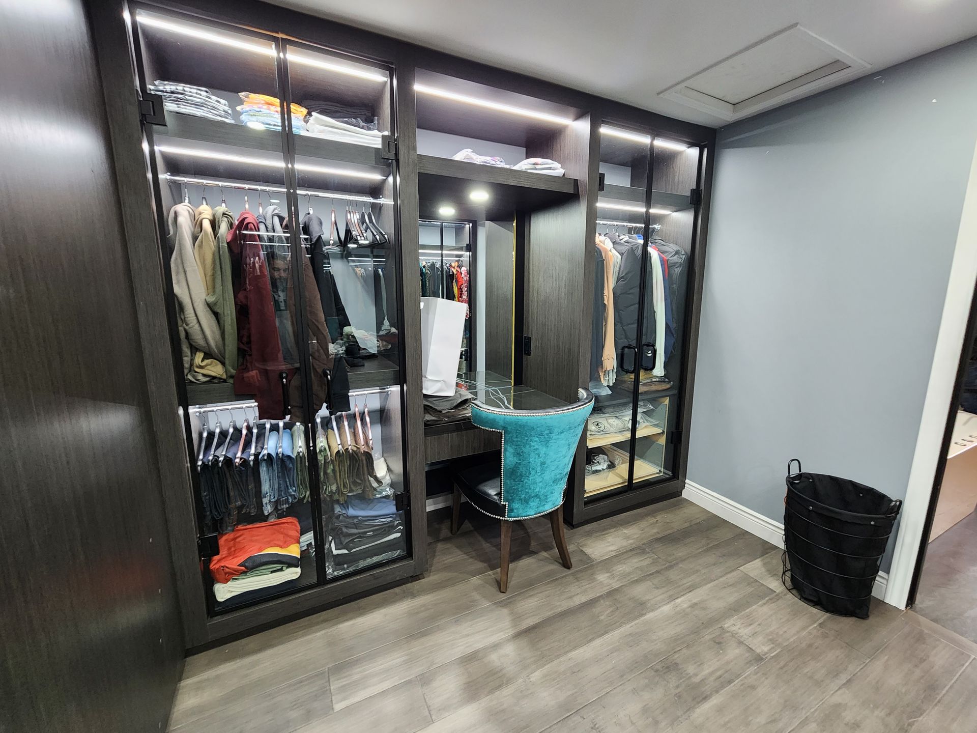 A woman is sitting at a desk in a walk in closet.