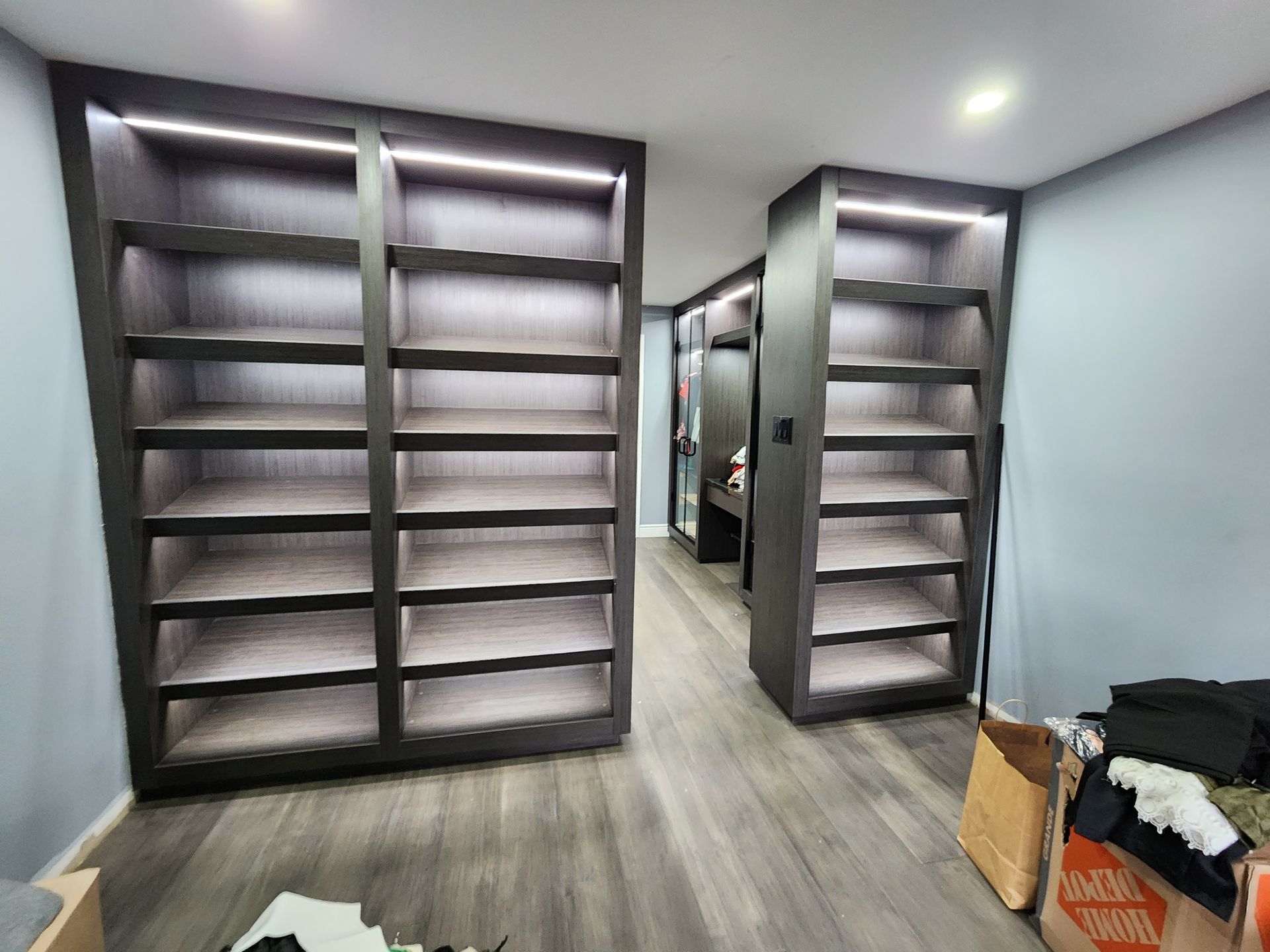A walk in closet with lots of shelves and lights.