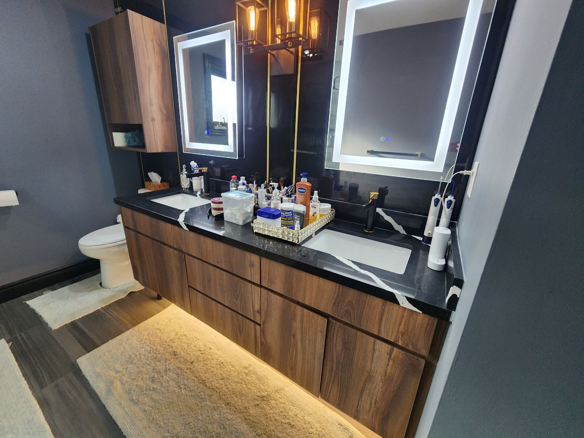 A bathroom with two sinks , two mirrors and a toilet.