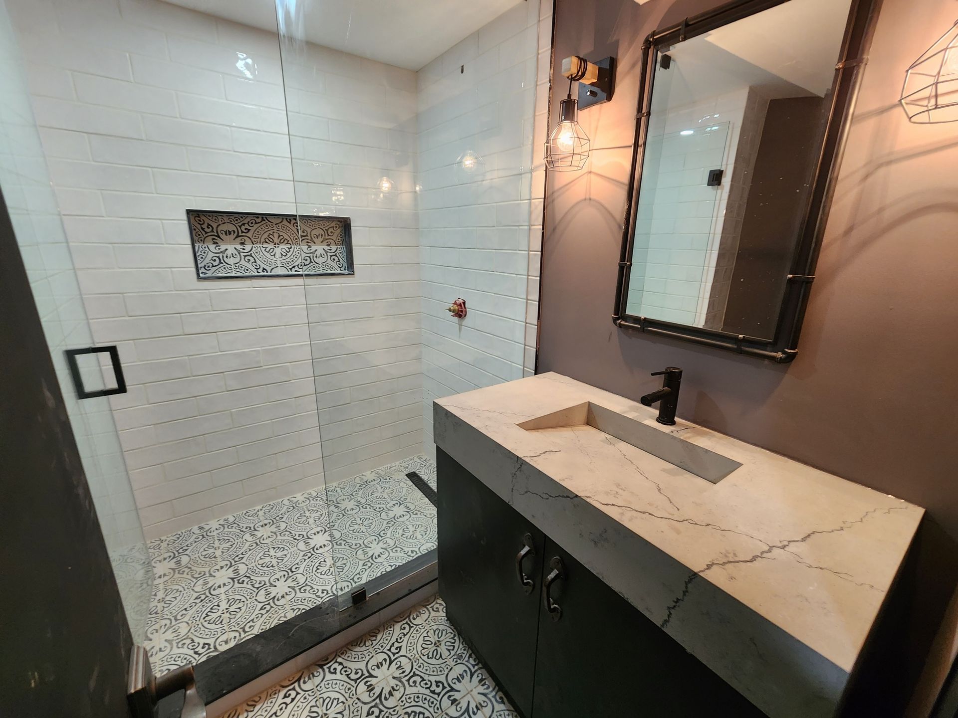 A bathroom with a sink , mirror and walk in shower.