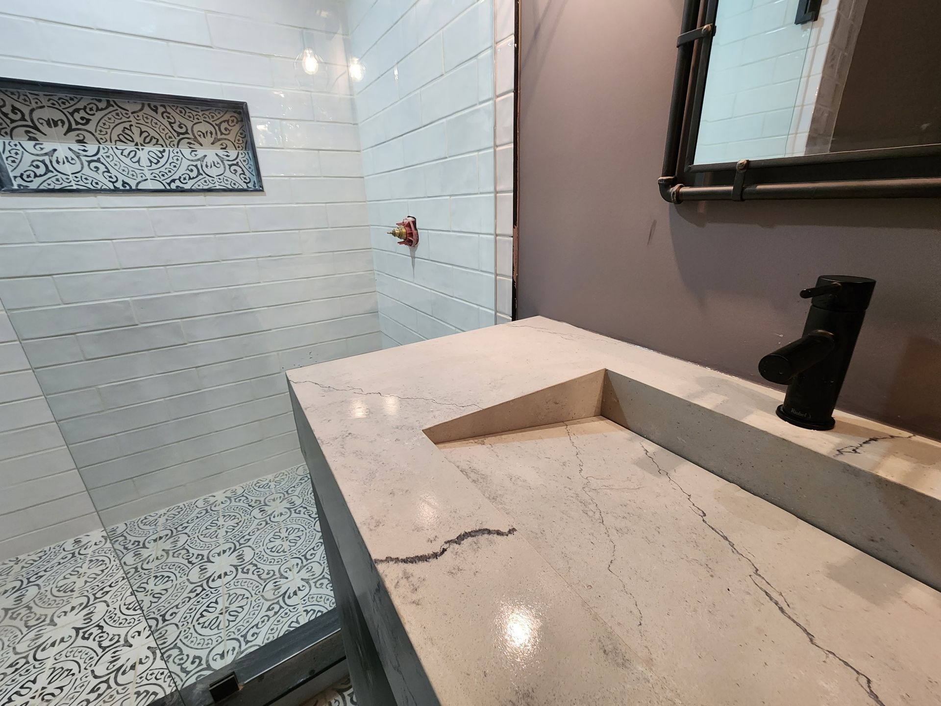 A bathroom with a sink , mirror and walk in shower.