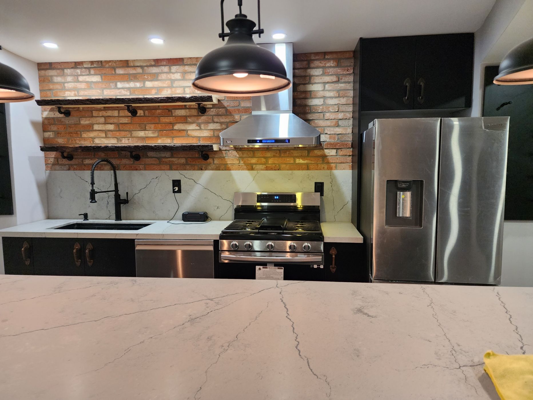 A kitchen with stainless steel appliances and a brick wall