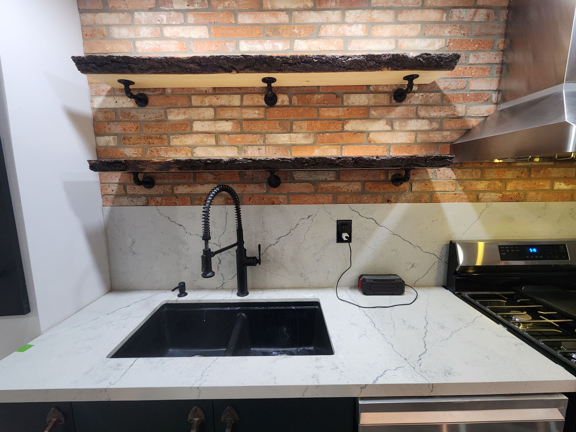 A kitchen with a sink , stove and brick wall