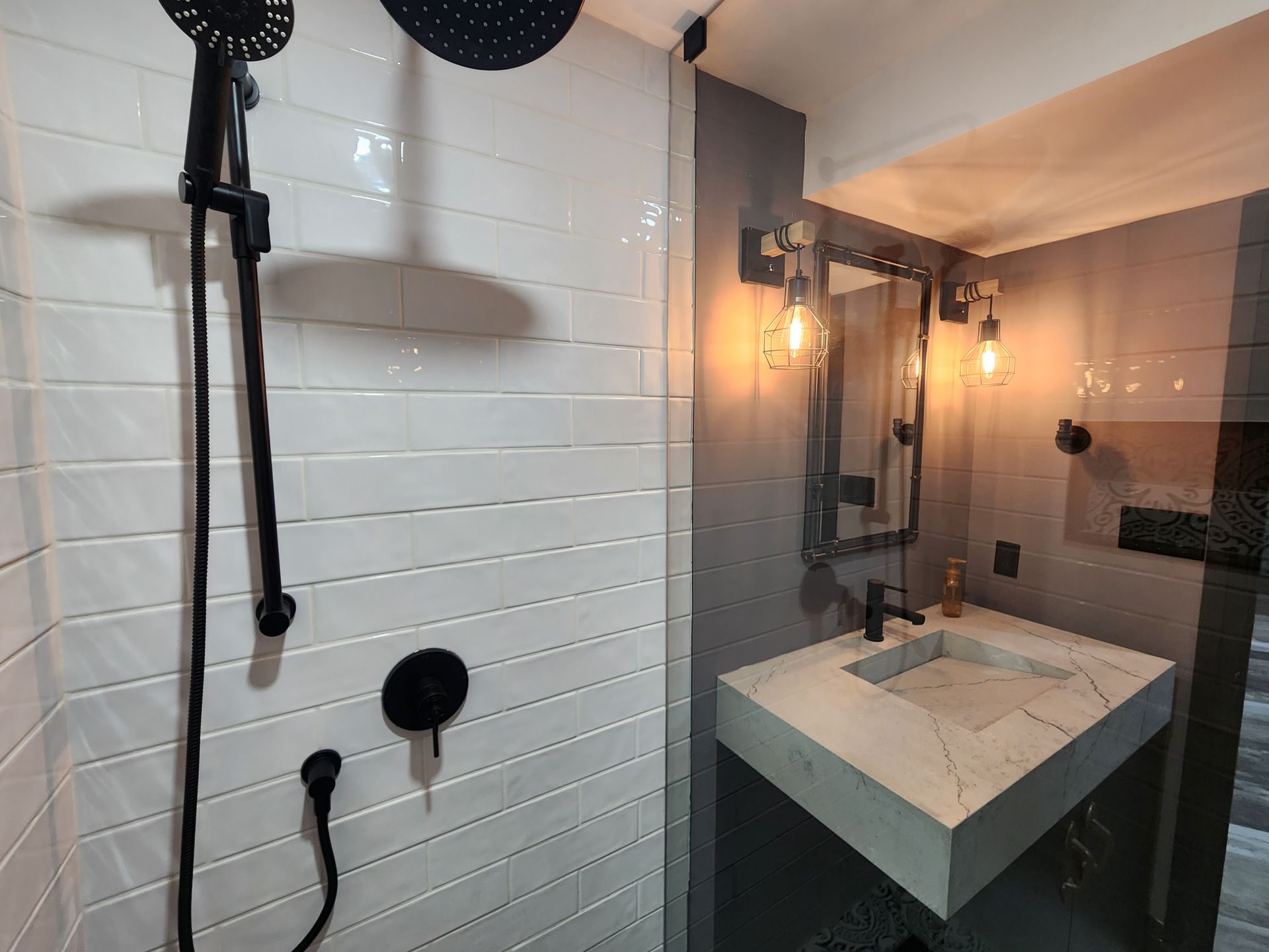 A bathroom with a sink , shower and mirror.