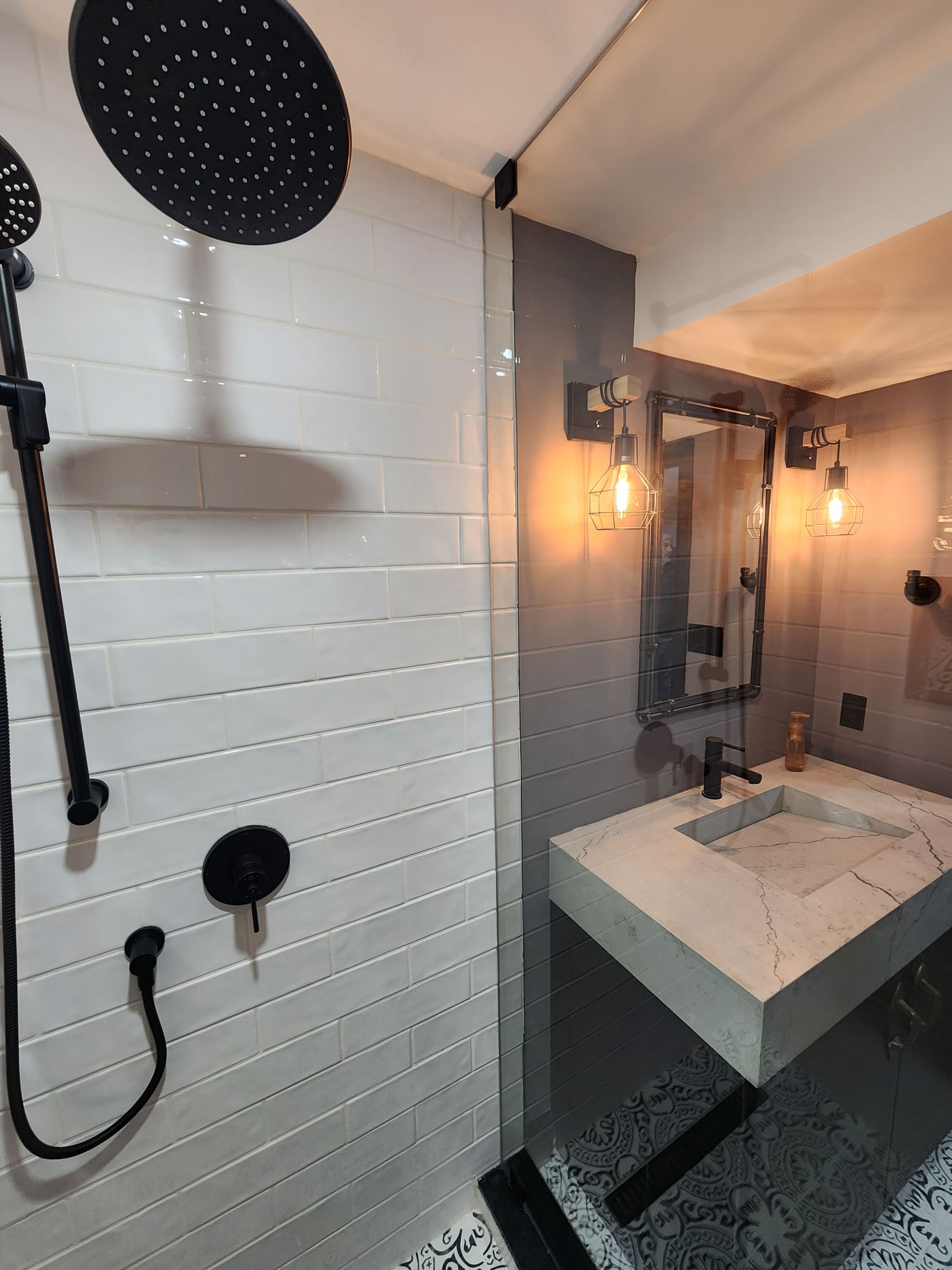 A bathroom with a sink , shower and mirror.