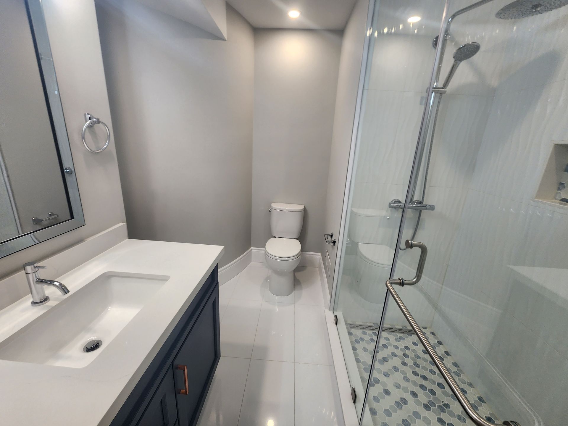 A bathroom with a toilet , sink and shower.