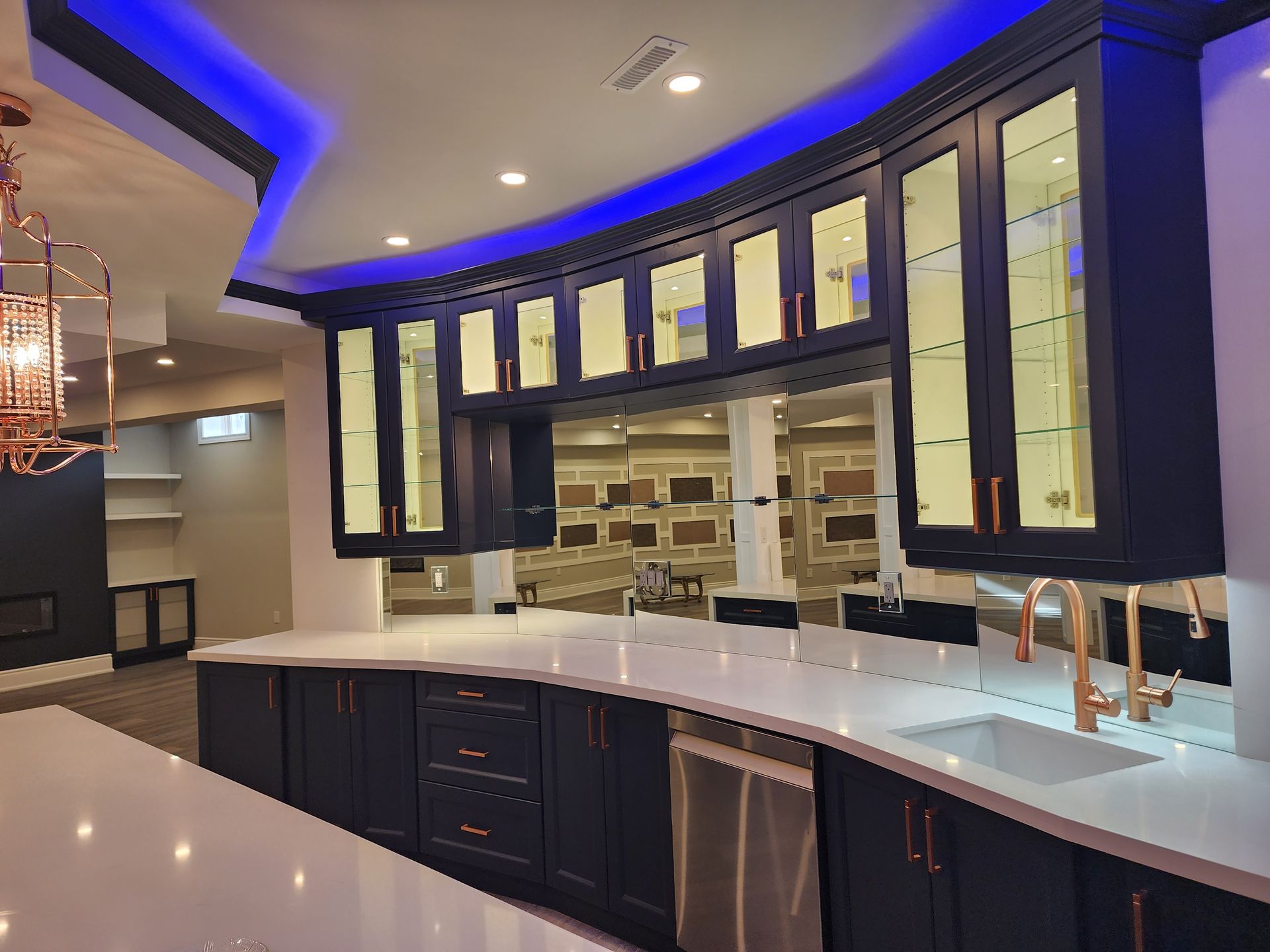 A kitchen with blue cabinets , white counter tops , and a sink.