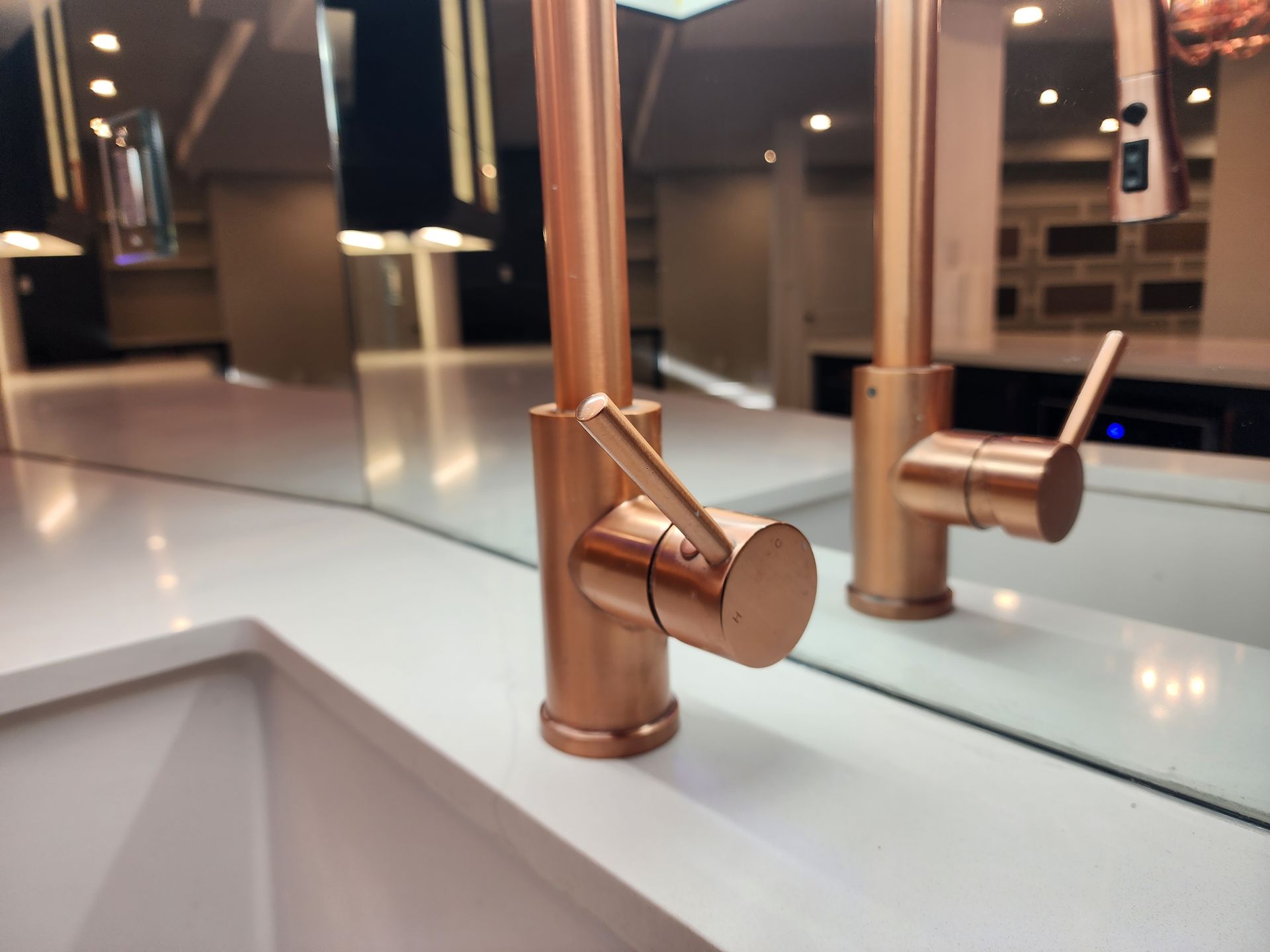 A bathroom sink with a copper faucet and a mirror