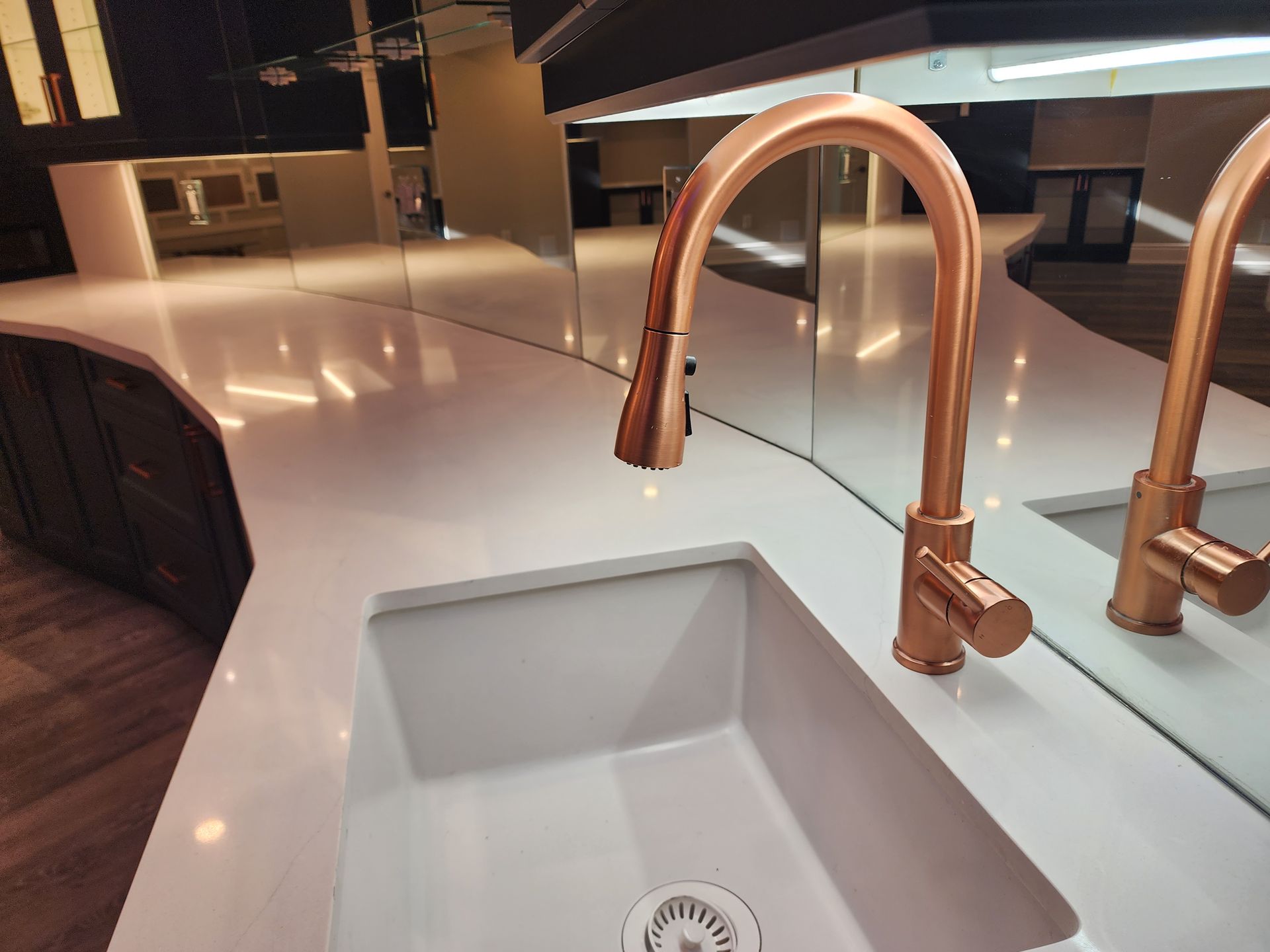 A kitchen sink with two copper faucets and a mirror