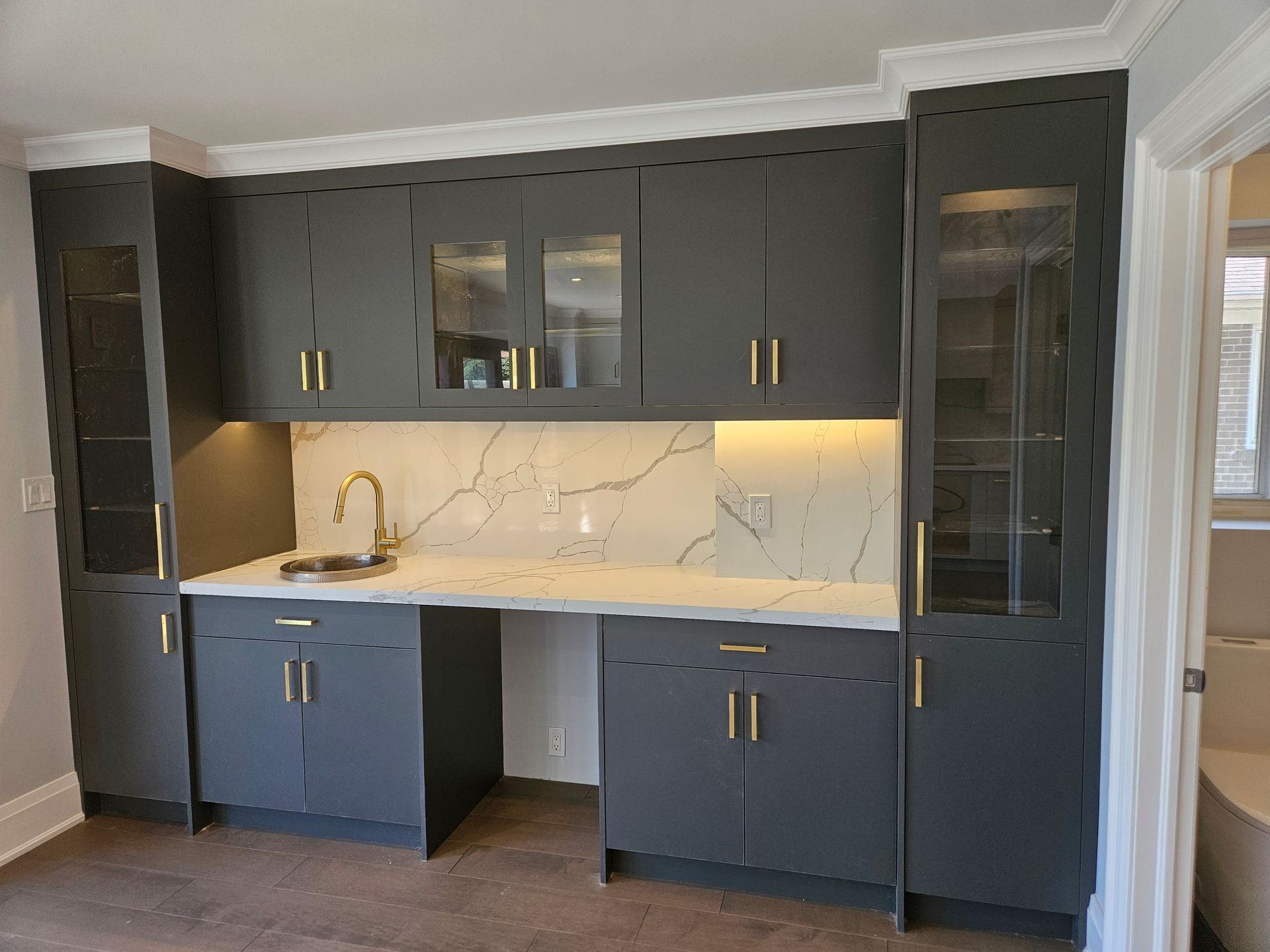 A kitchen with gray cabinets and white counter tops.