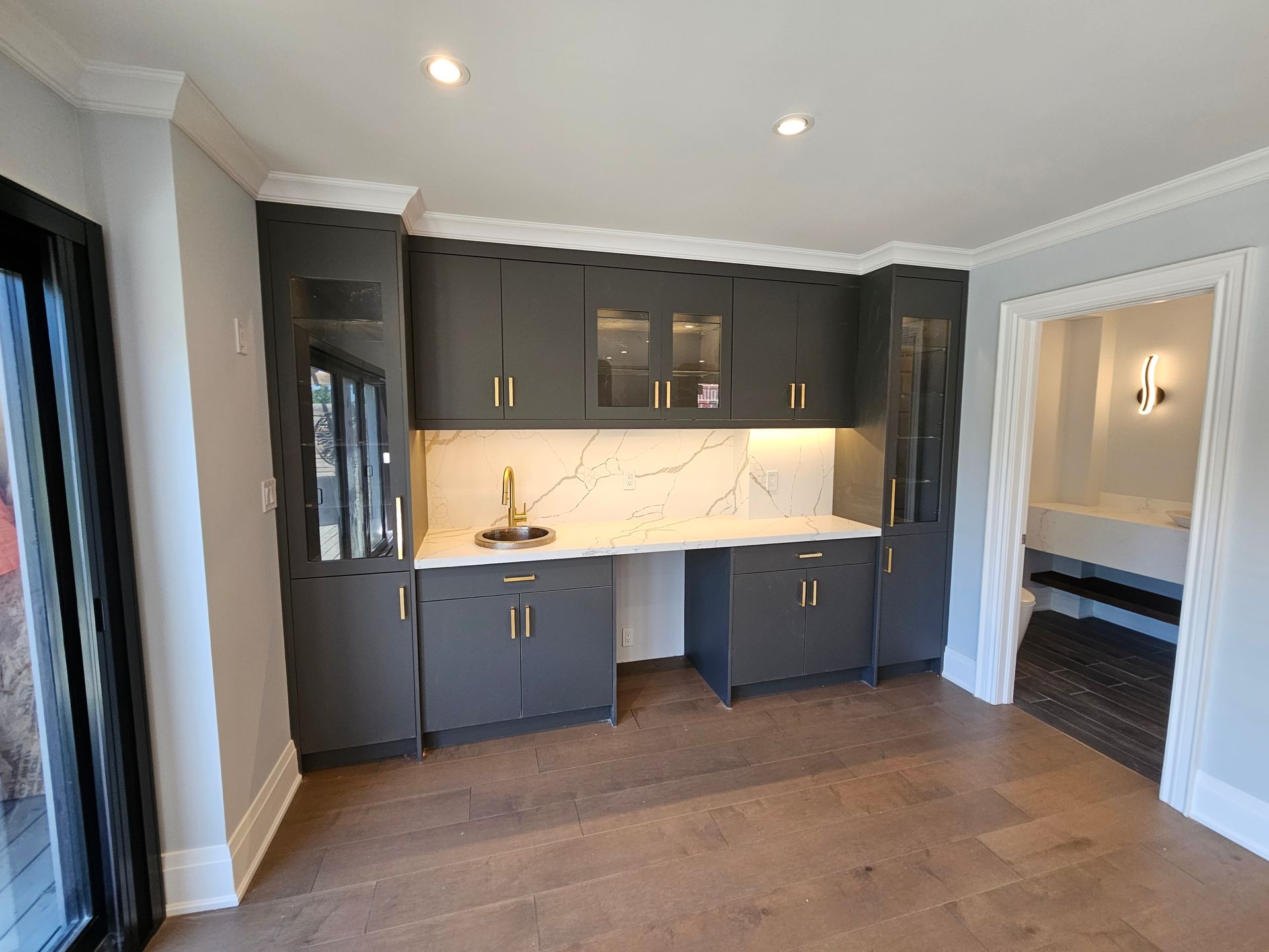 A kitchen with black cabinets and white counter tops in a house.