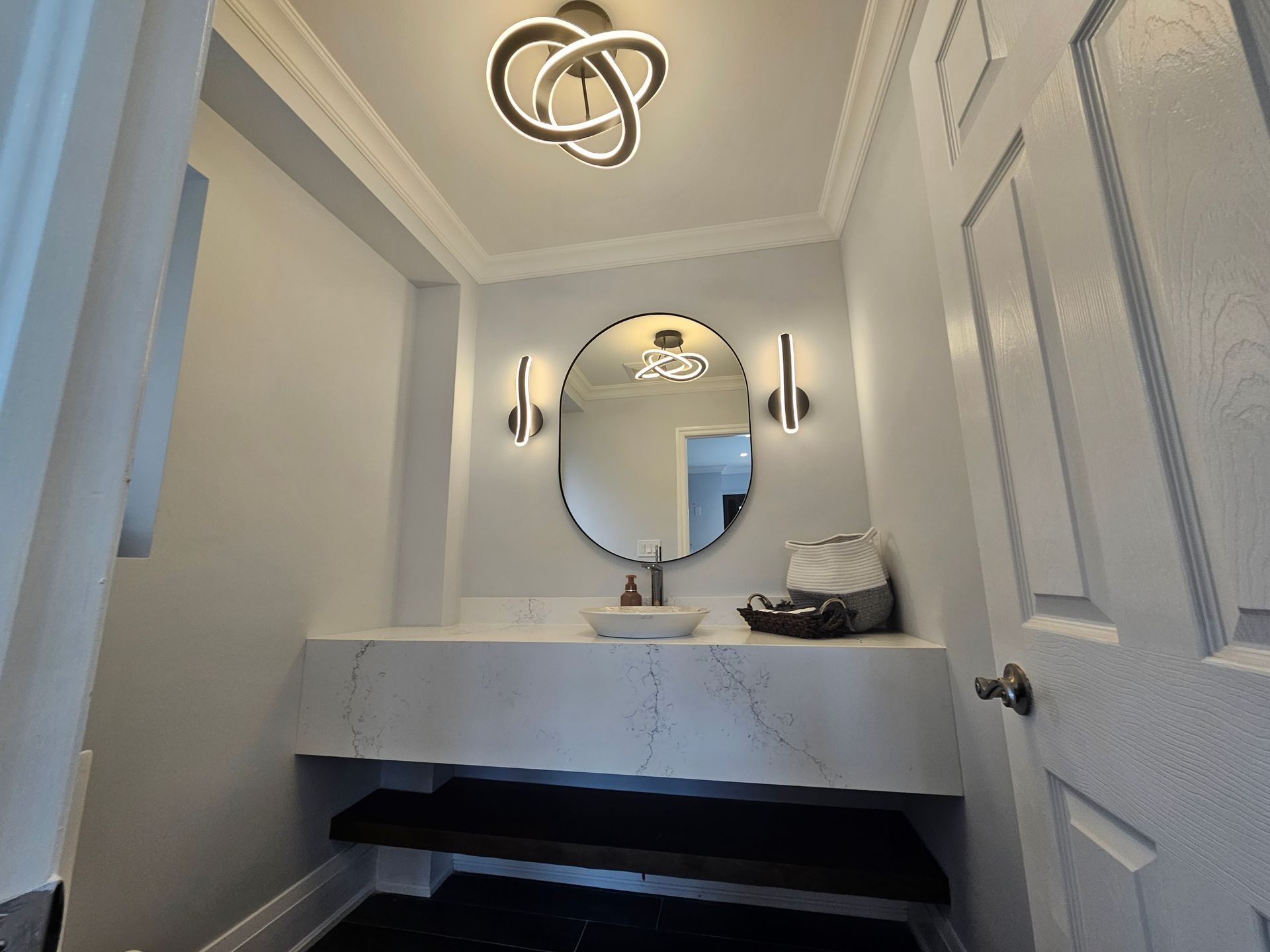 A bathroom with a sink , mirror , and stairs.