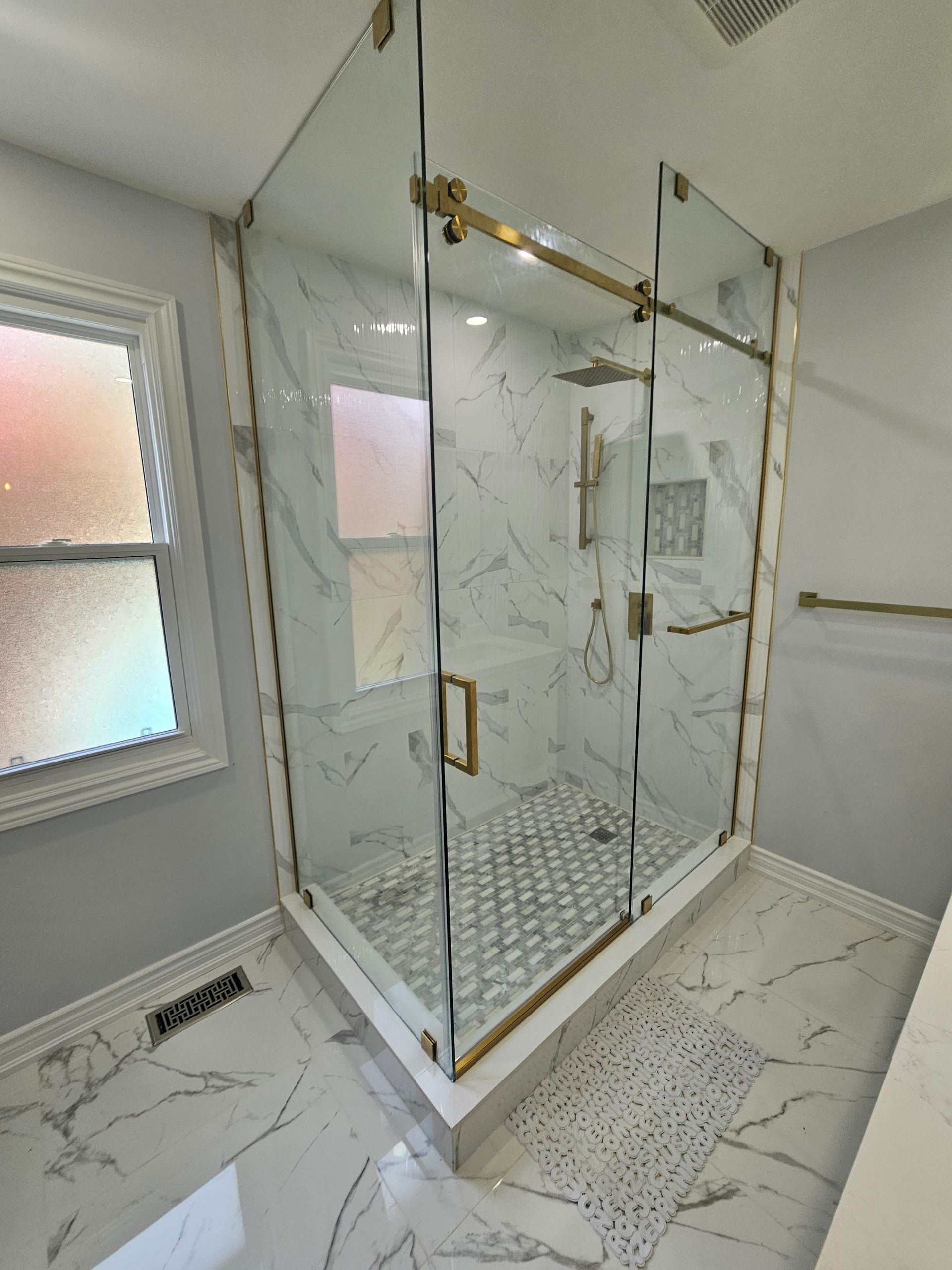 A bathroom with a walk in shower and a window.