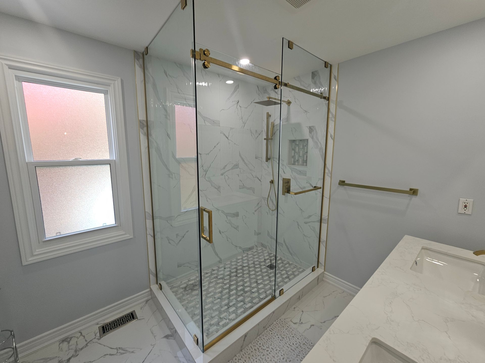 A bathroom with a walk in shower and a sink.