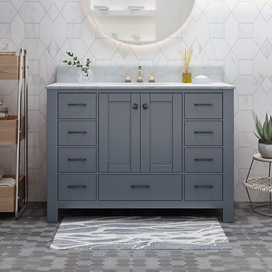 A bathroom with a gray vanity , sink and mirror.