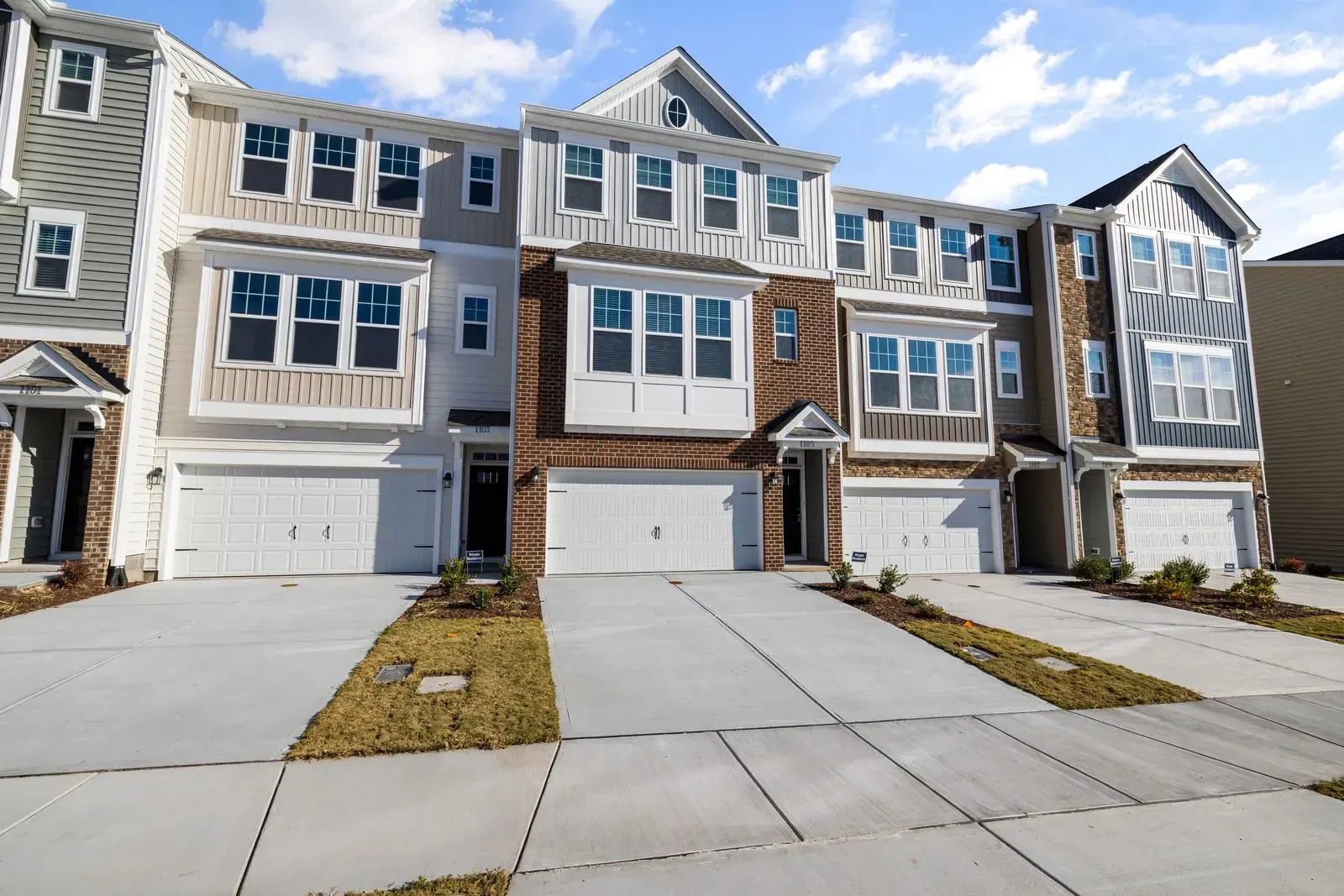 A row of houses with a concrete driveway in front of them