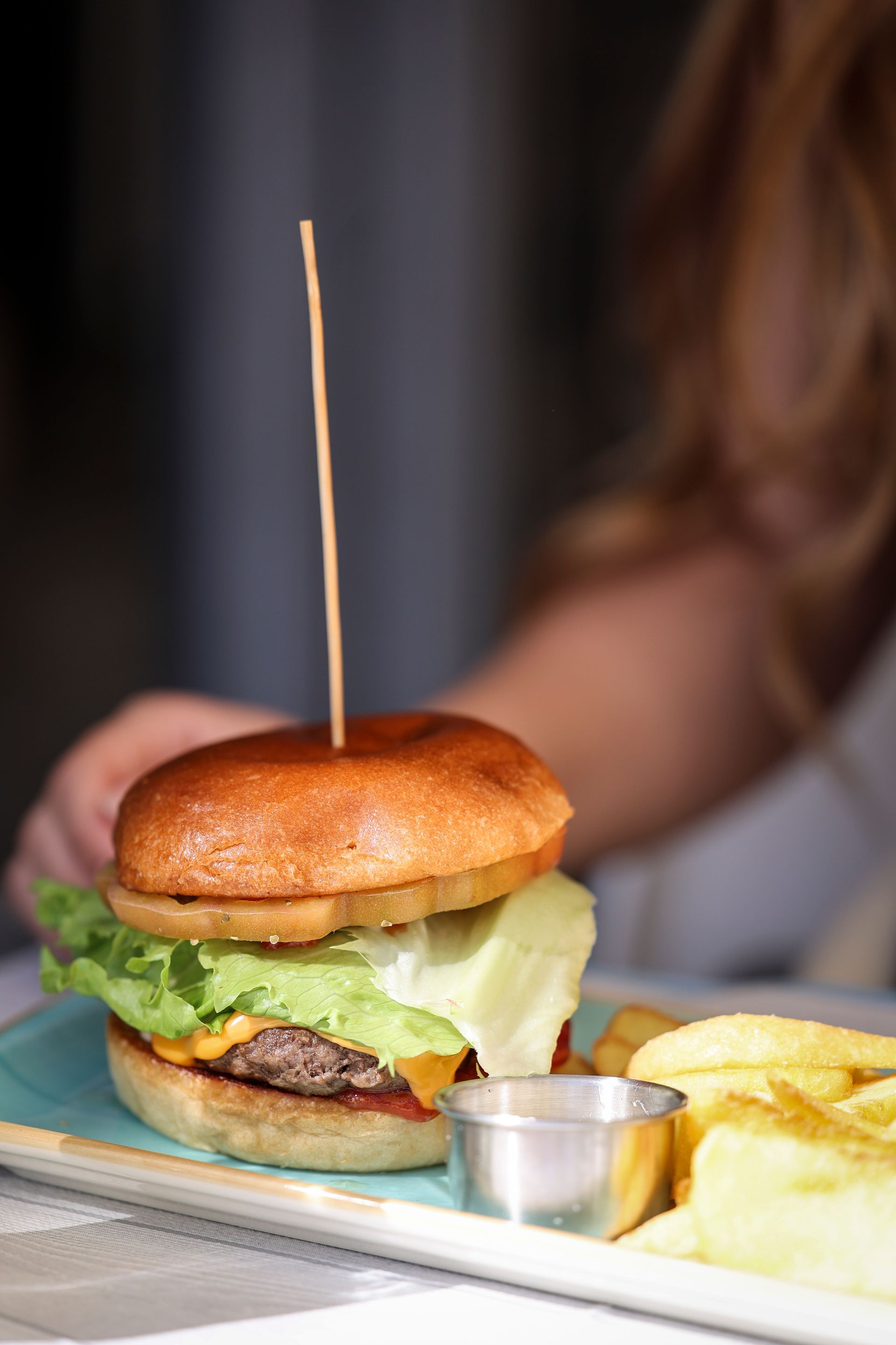 Hamburger e patatine fritte su un tavolo, con una mano che si protende verso il pasto.