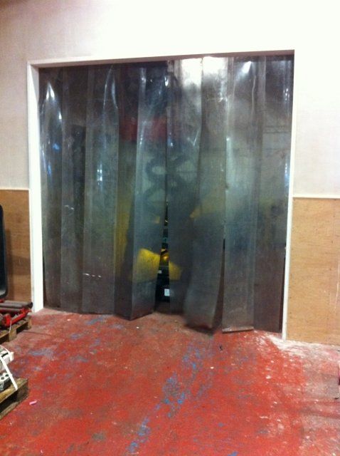 A clear plastic curtain is covering a door in a garage.