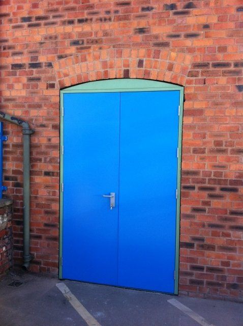 A blue door is against a brick wall
