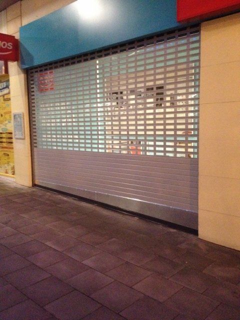 A store with a closed shutter and a sign that says ' ros ' on it